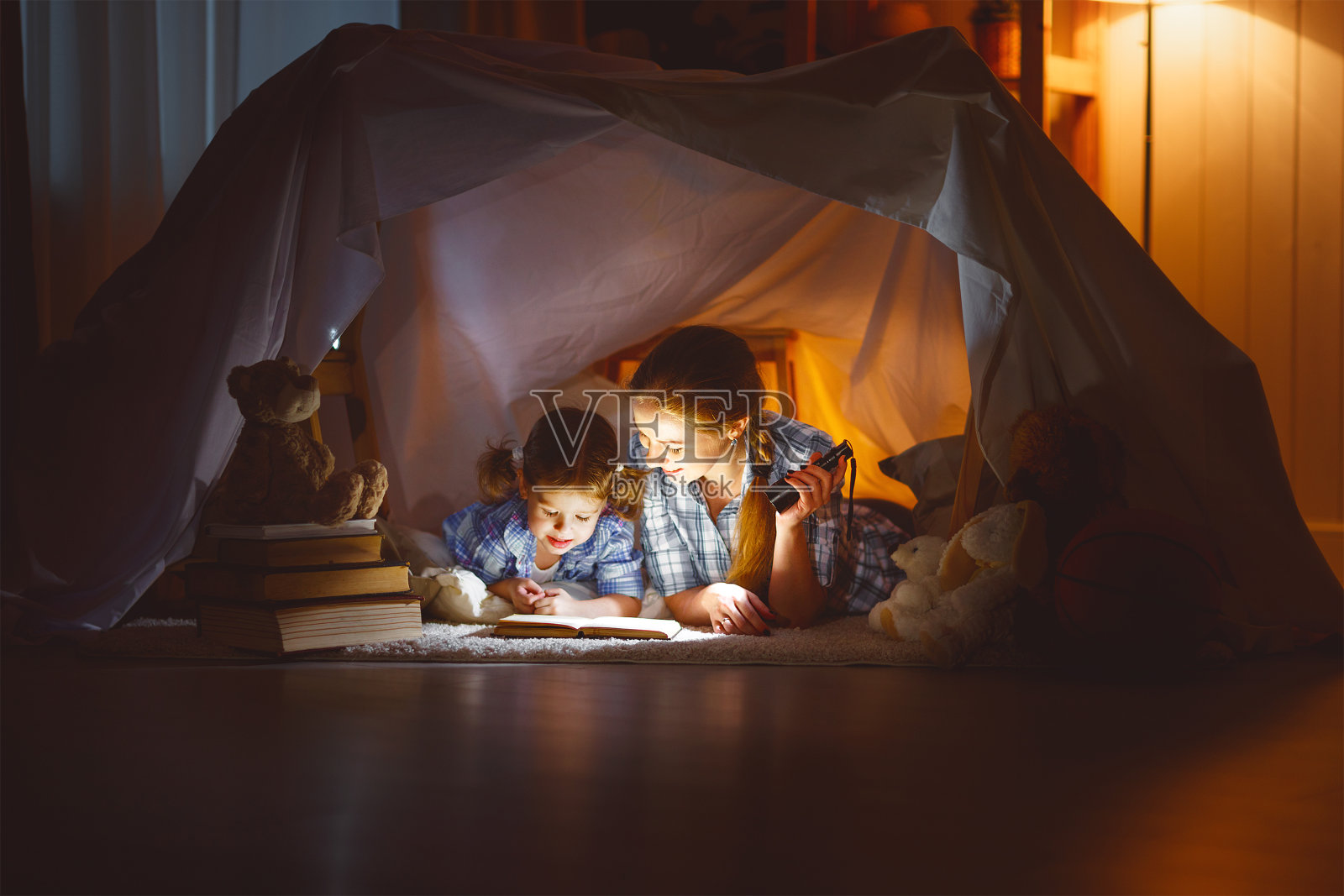 母亲和孩子在睡觉前拿着一本书和一个手电筒照片摄影图片