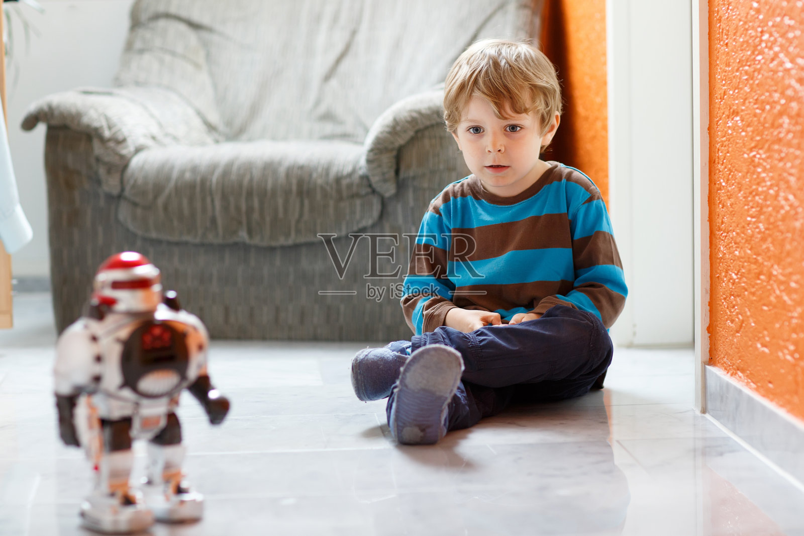 金发小男孩在家玩机器人玩具，在室内。照片摄影图片