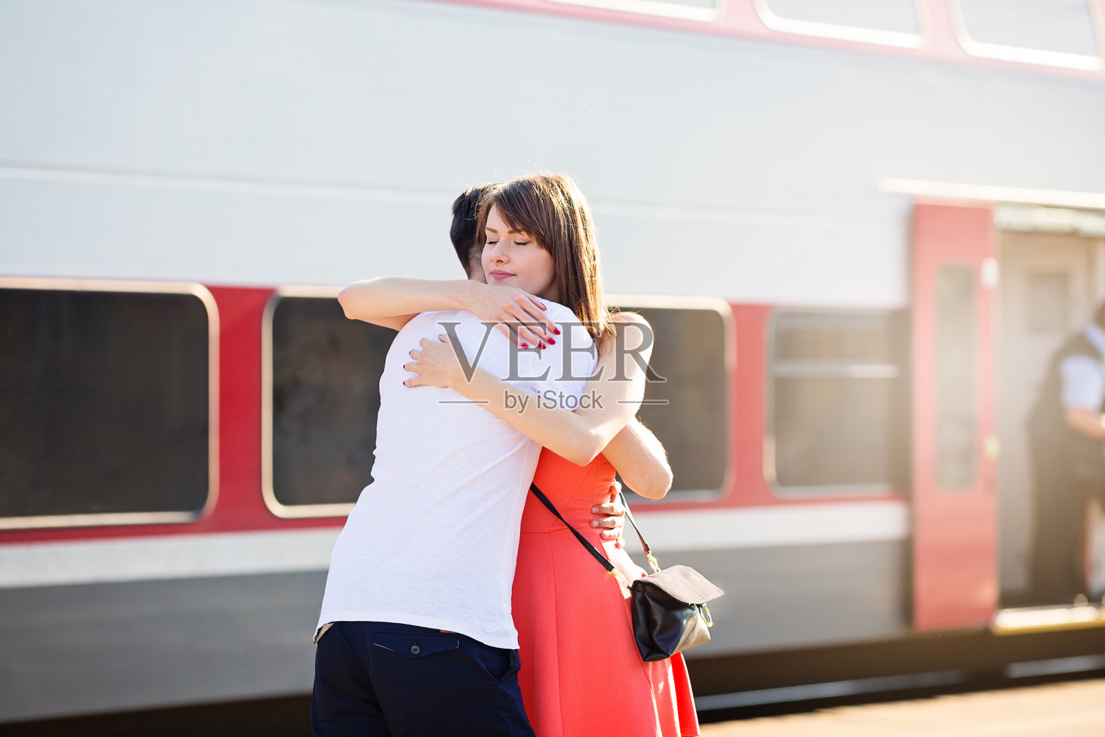 一对年轻的白人夫妇站在火车站，拥抱着告别照片摄影图片