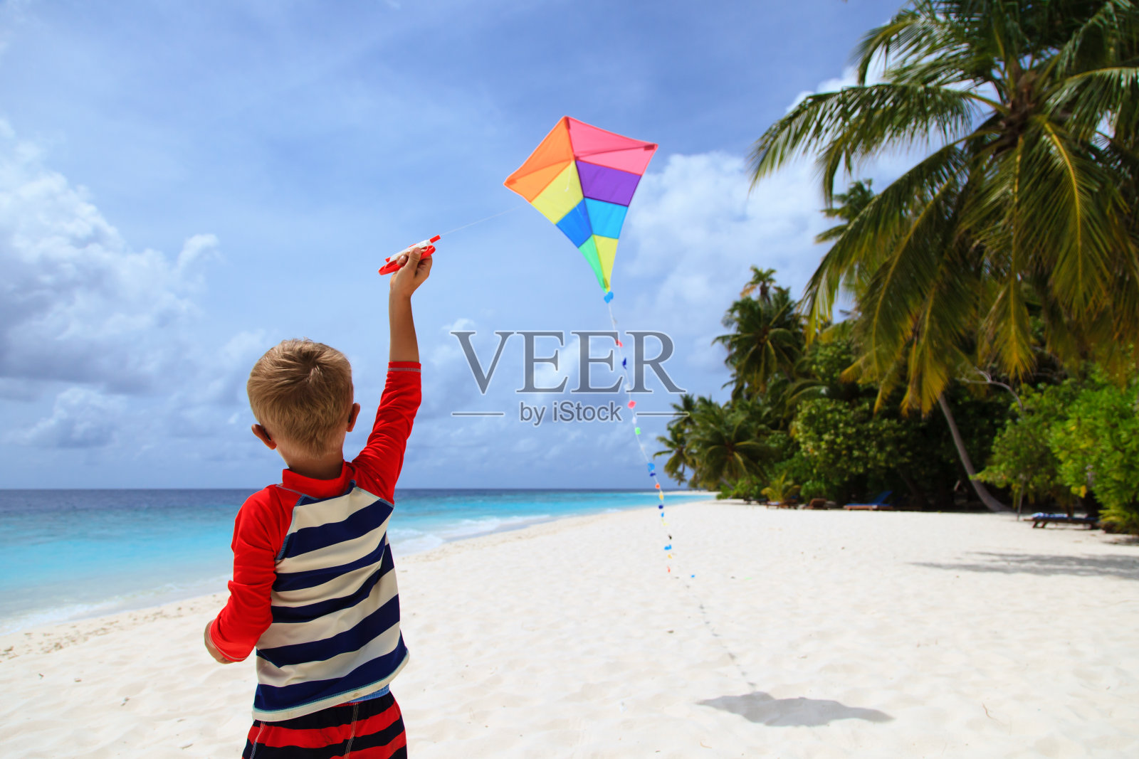 小男孩在热带海滩上放风筝照片摄影图片