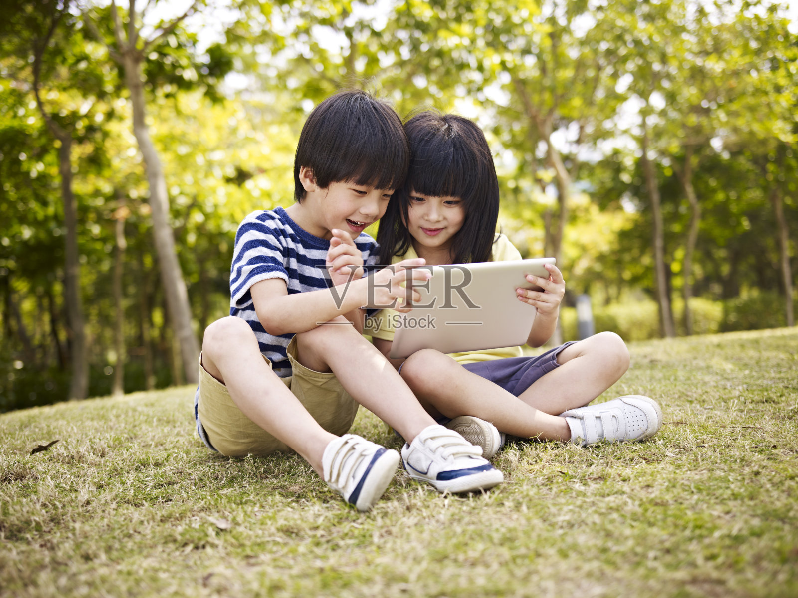 两个亚洲儿童在户外使用平板电脑照片摄影图片