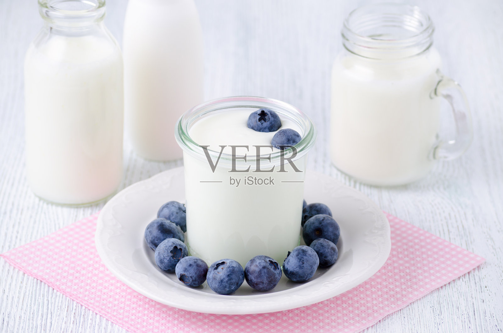 桌上放着一杯蓝莓酸奶和不同的酸奶饮料和牛奶照片摄影图片