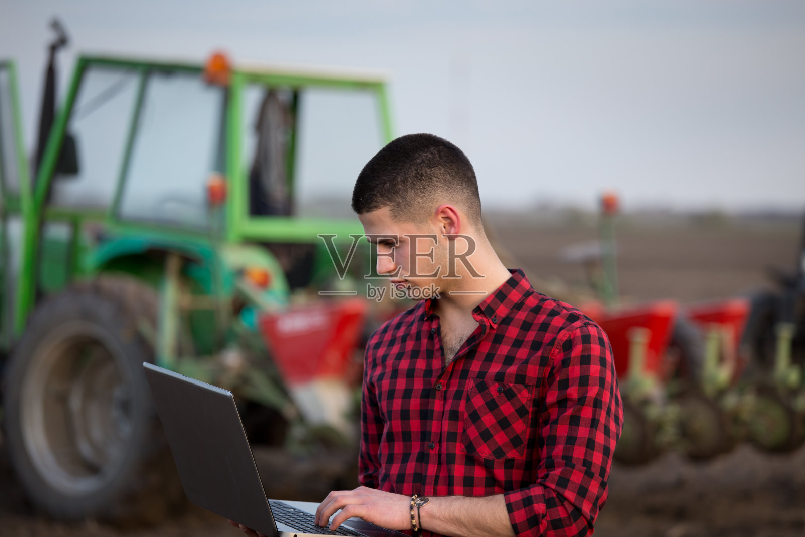 农民把笔记本电脑放在农用设备前照片摄影图片
