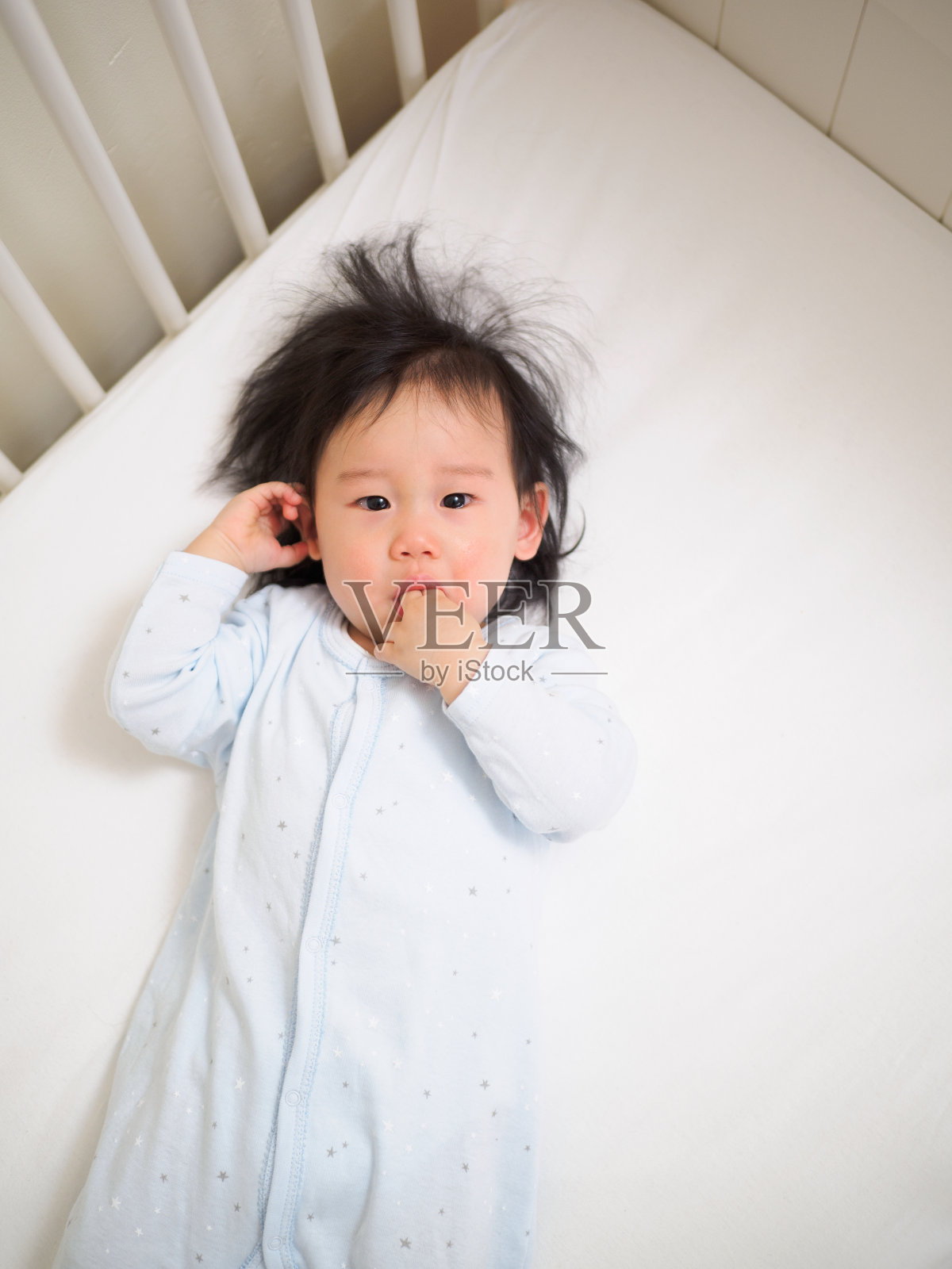 婴儿床里哭的小女孩照片摄影图片
