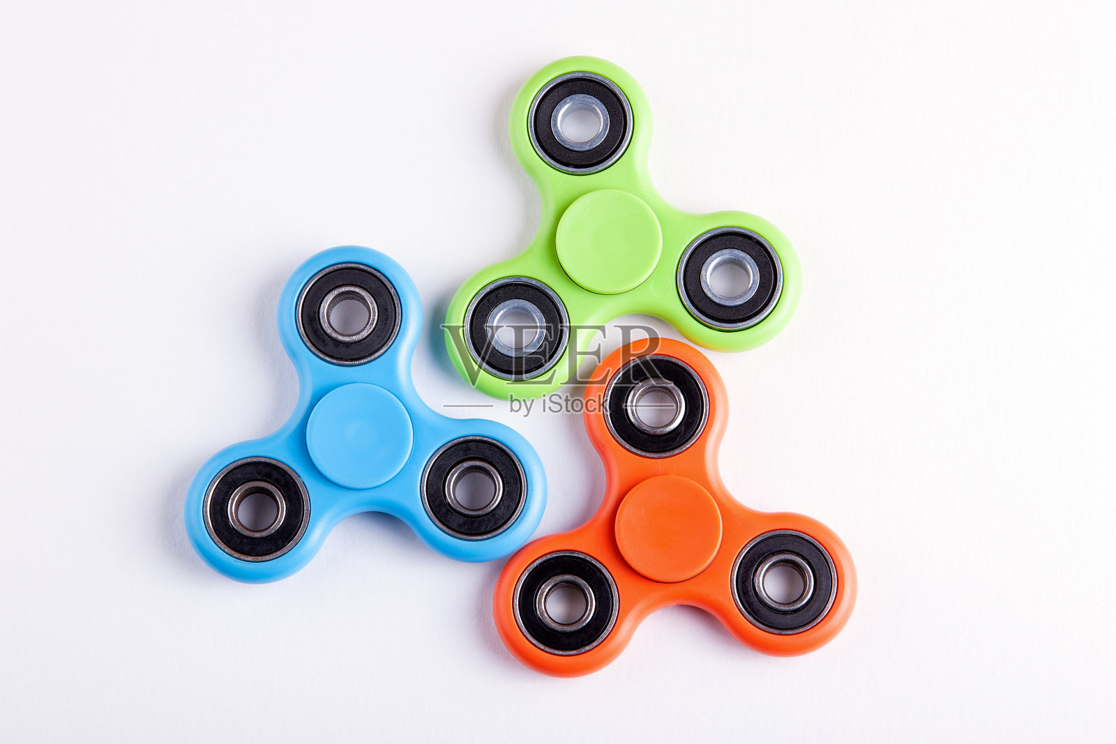 绿色，蓝色和橙色指尖陀螺应力缓解玩具在白色的背景照片摄影图片