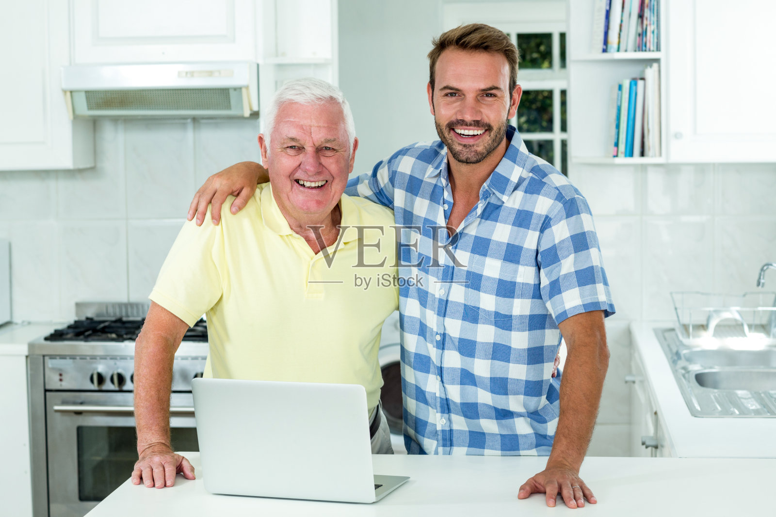 一个男人和父亲站在厨房的桌子上，用笔记本电脑照片摄影图片