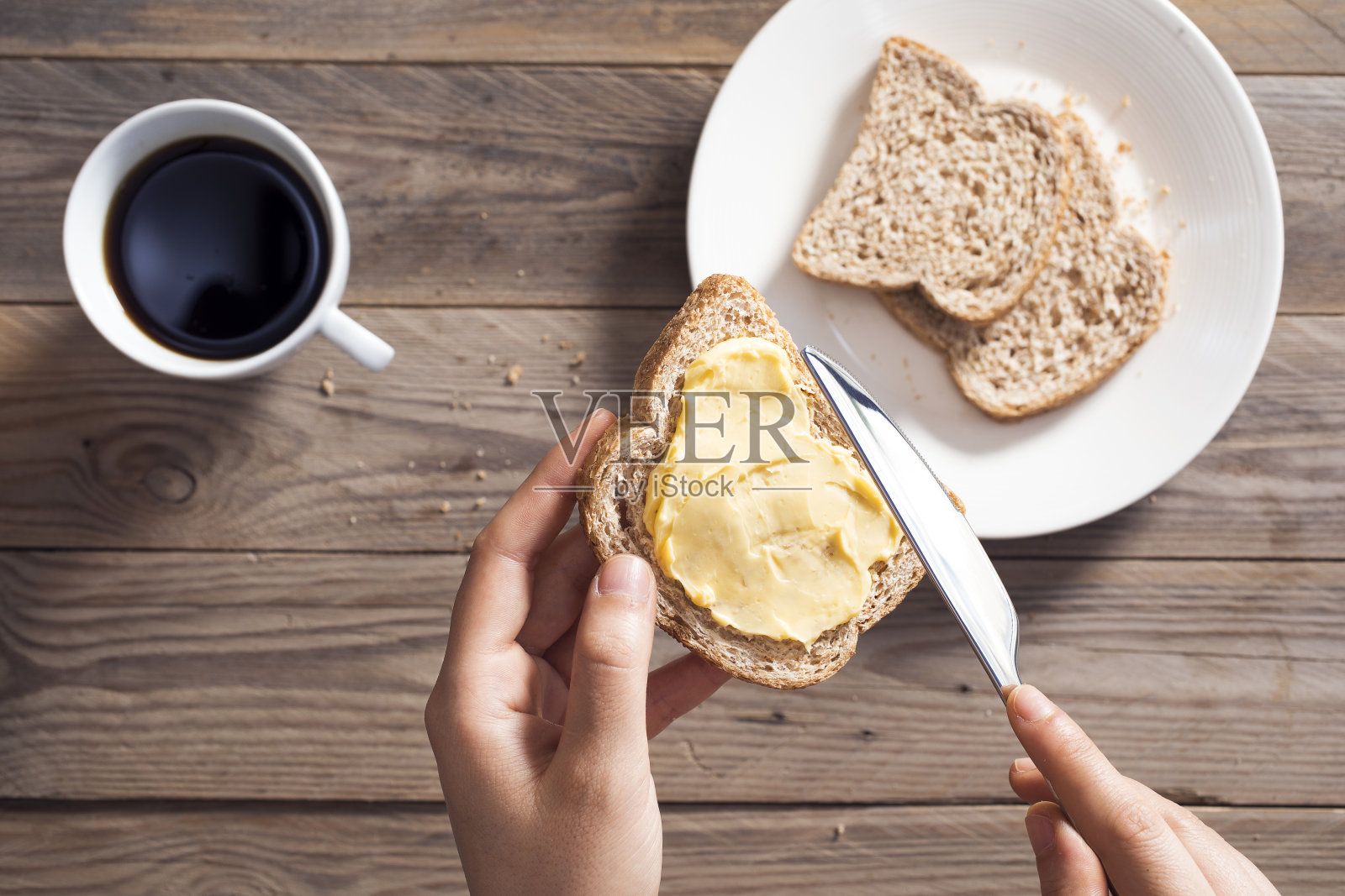女人用手把黄油涂在切片面包上照片摄影图片