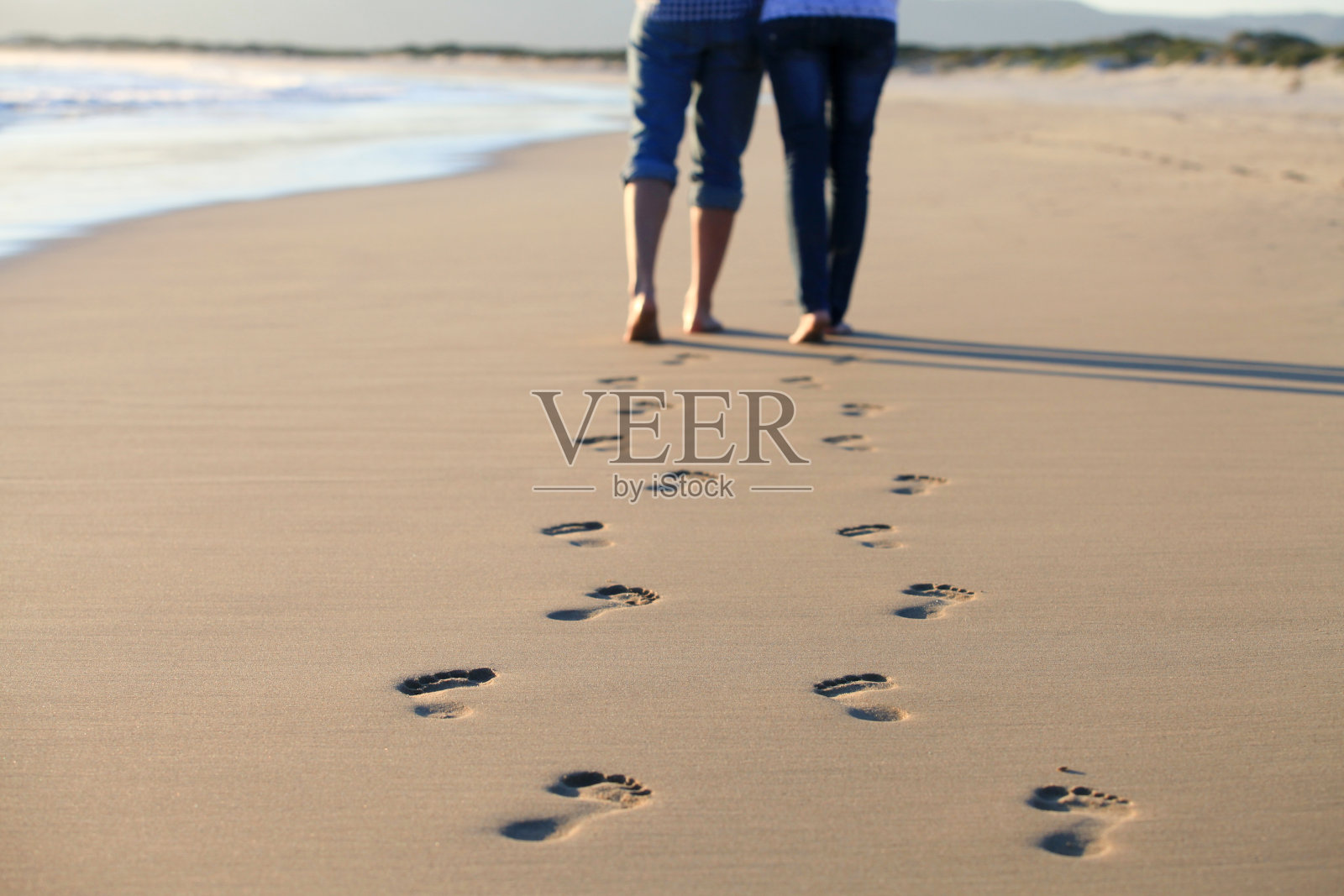 夫妇走过海滩，留下脚印照片摄影图片
