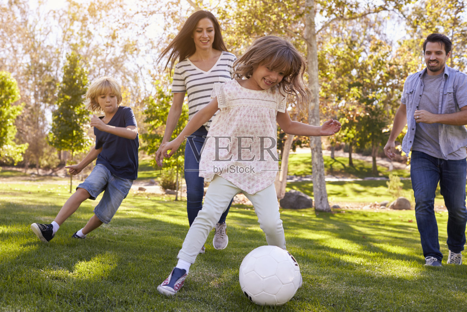 一家人一起在公园里踢足球照片摄影图片