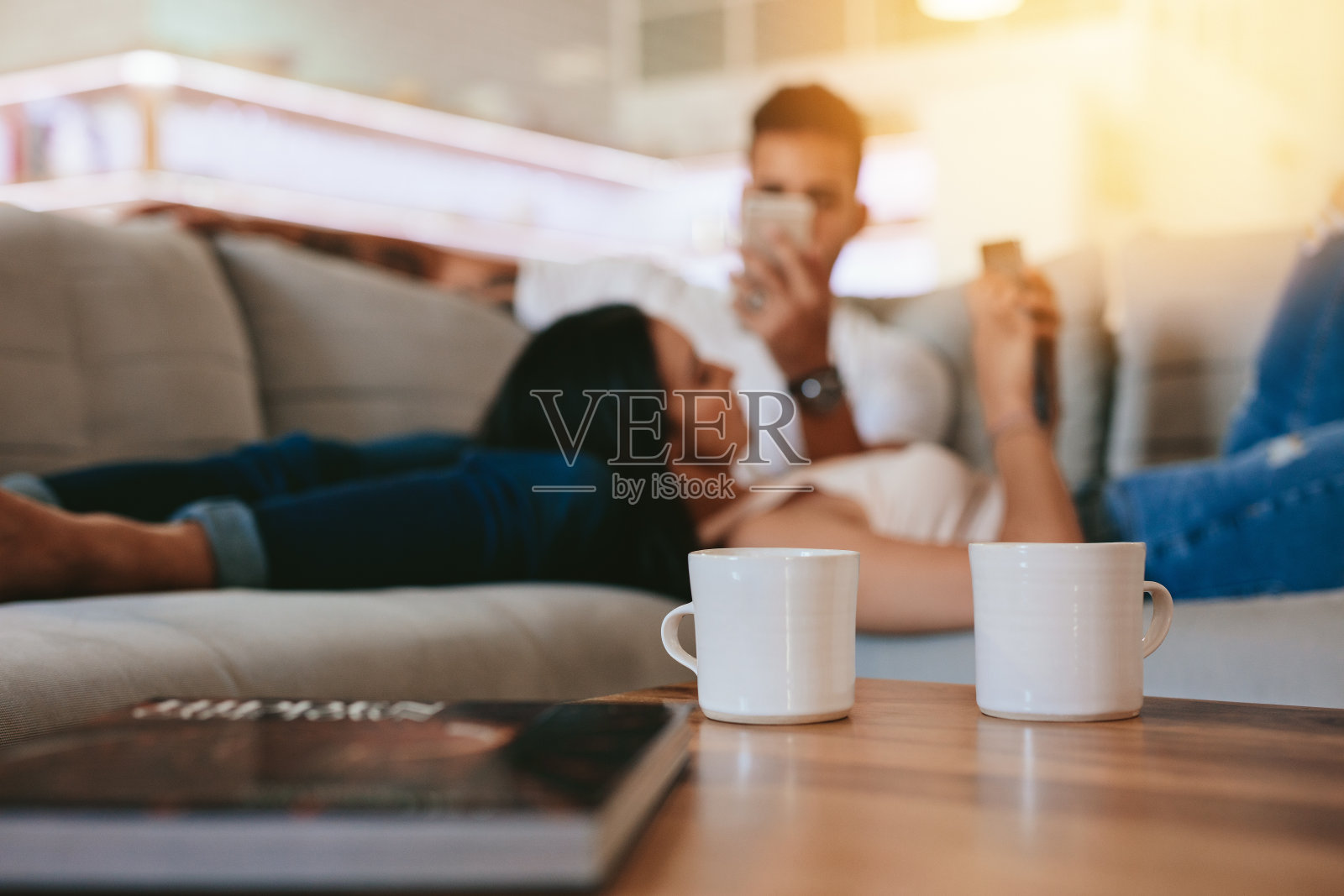 桌上放着咖啡杯，背景是一对放松的情侣照片摄影图片