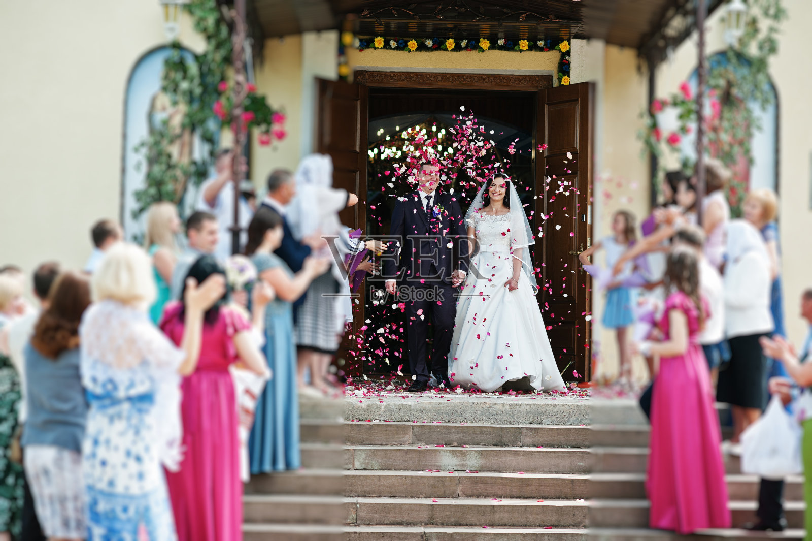 出教堂时，客人们用玫瑰花瓣迎接新婚夫妇。照片摄影图片