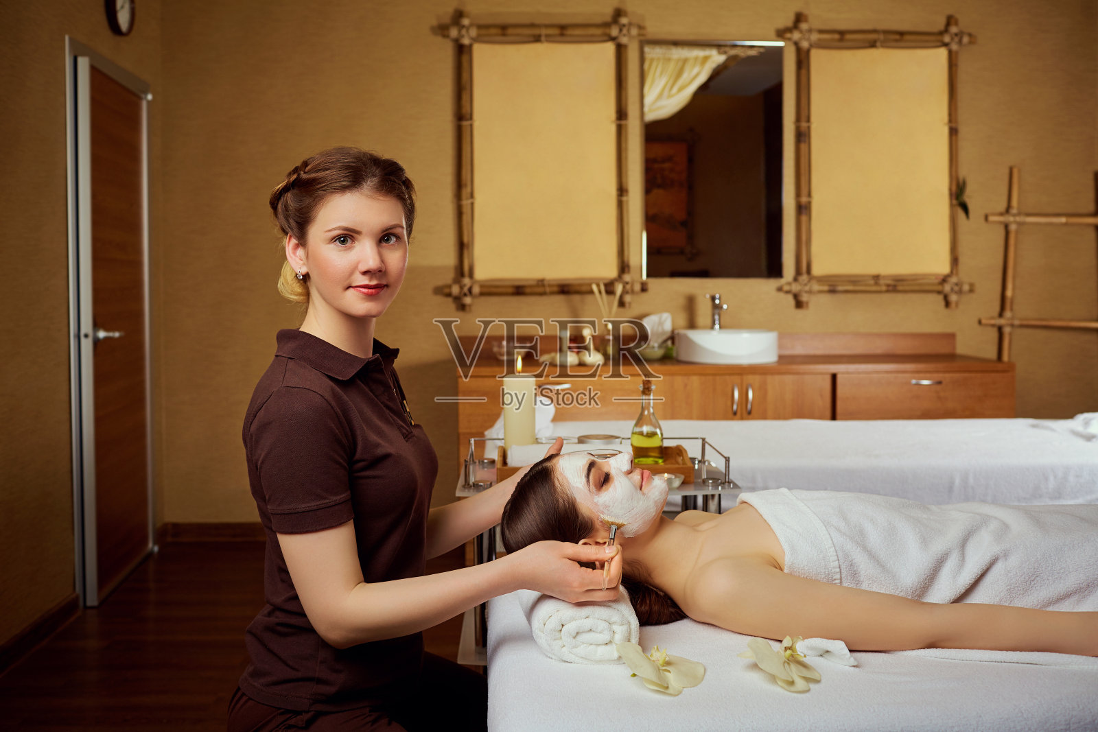 美容师在水疗沙龙为一个女人做面膜照片摄影图片