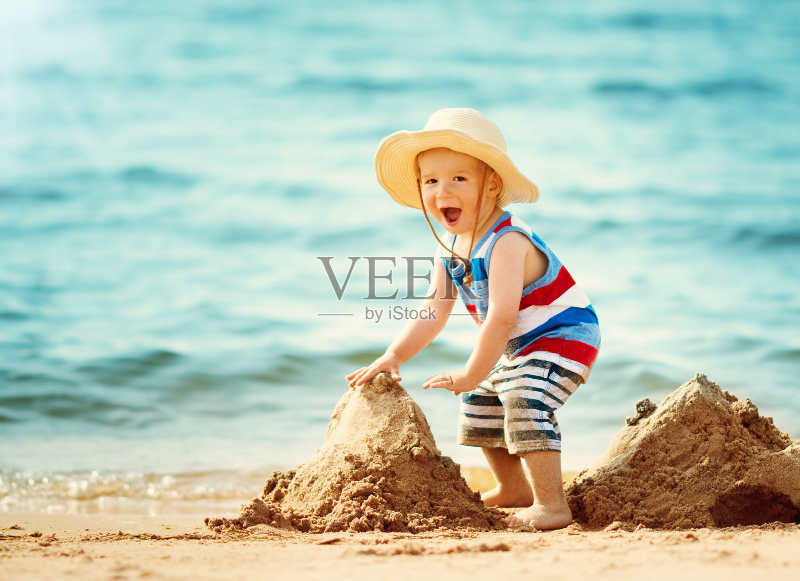 小男孩戴着草帽在海滩上散步照片摄影图片