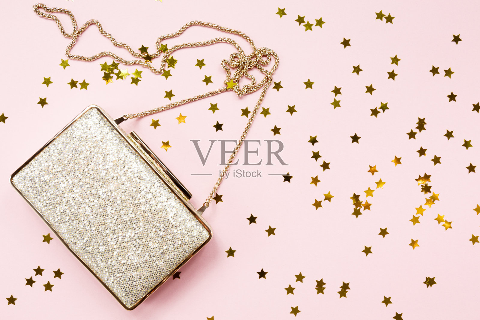 节日夜晚的金色手包与星星点缀粉红色。节日和庆典背景。奢华配饰和派对概念照片摄影图片