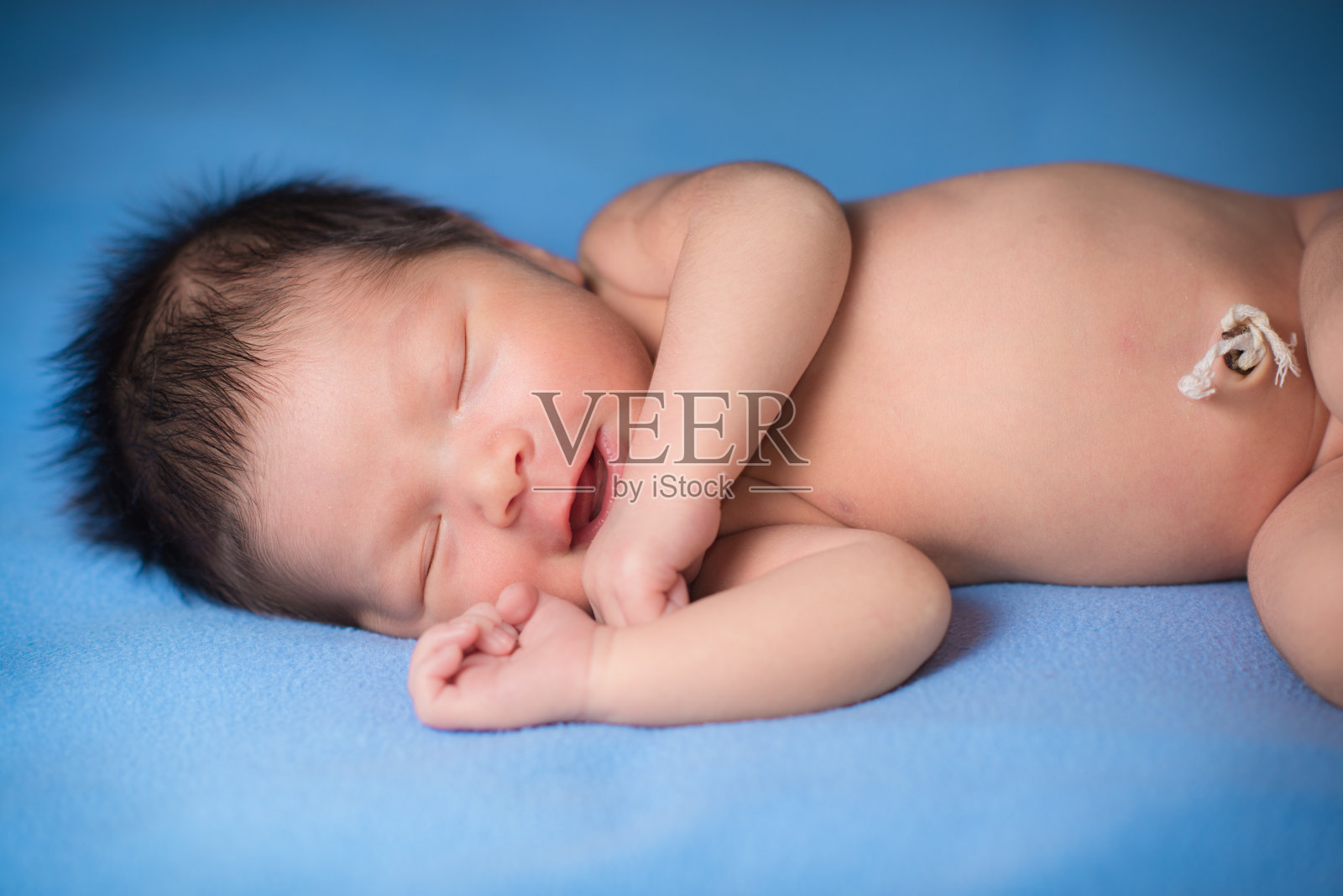 新生婴儿躺在蓝色毯子上照片摄影图片