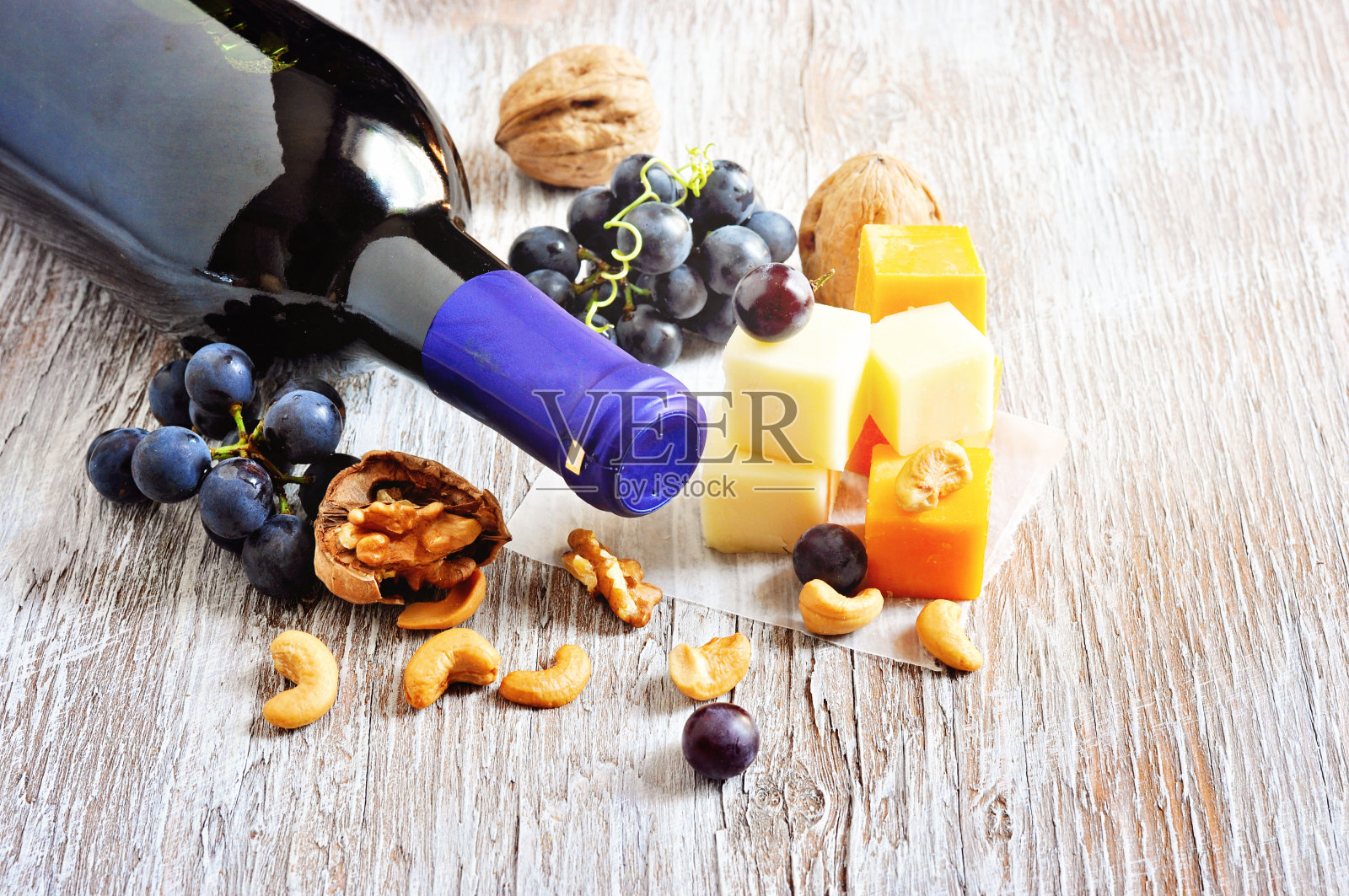 一瓶红酒，奶酪，核桃，腰果和葡萄。照片摄影图片