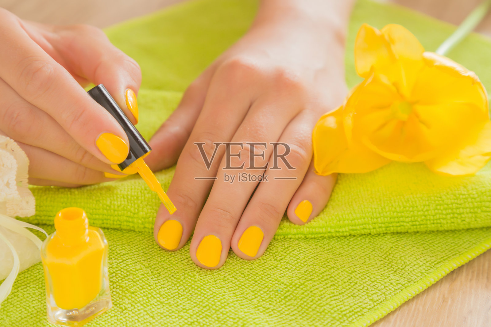 手在乎手指甲。修指甲美容院。黄色指甲油。春天和夏天的气氛与黄色和绿色的颜色。照片摄影图片