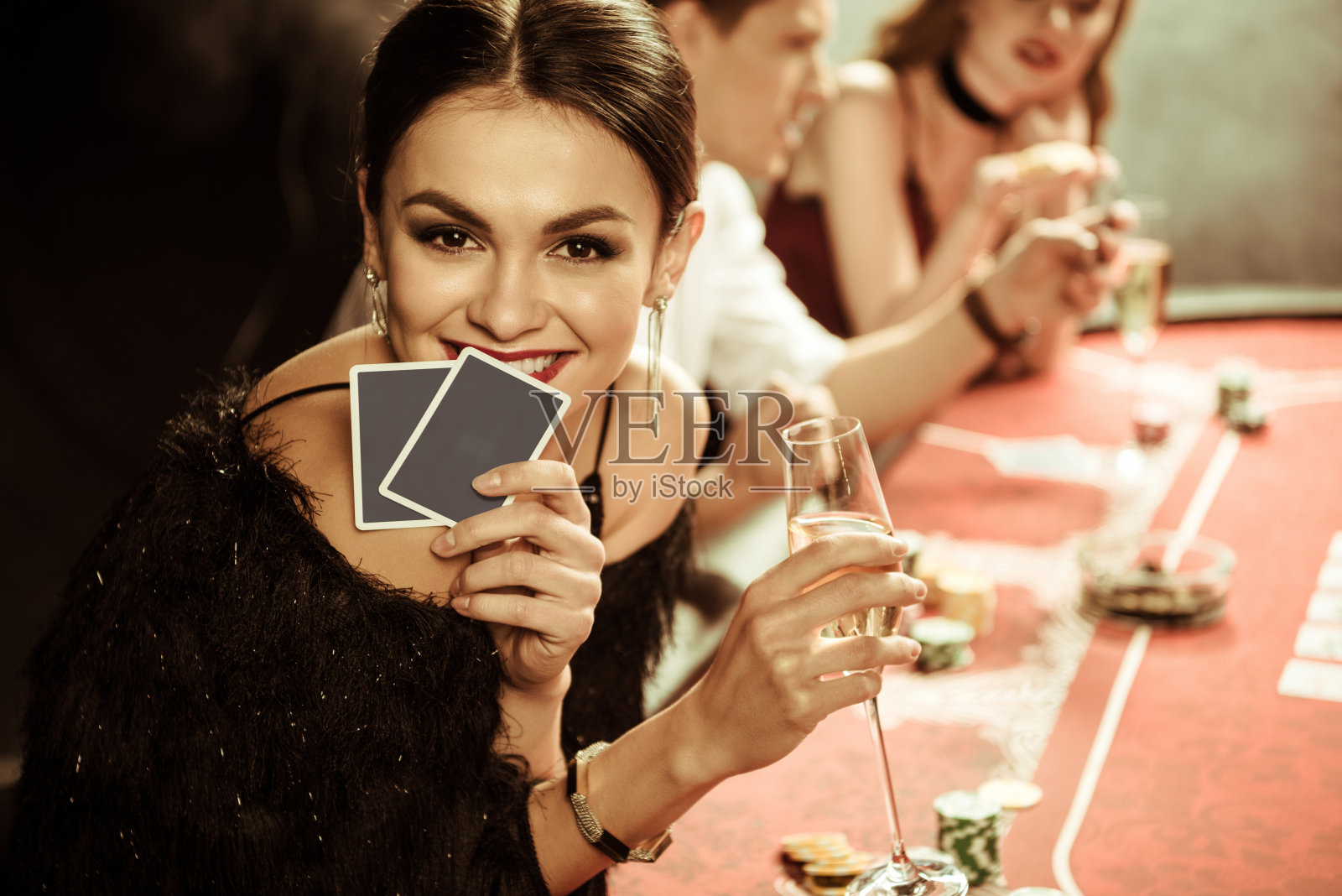 微笑女人的肖像，喝着酒，玩着扑克牌照片摄影图片