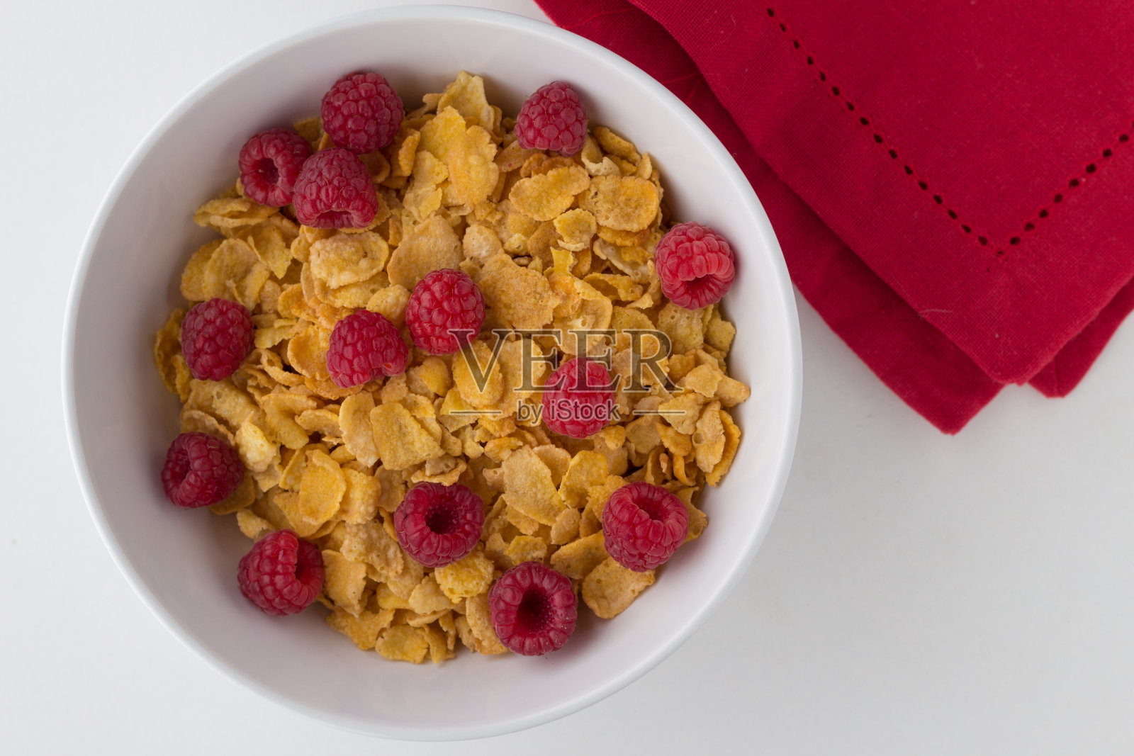 早餐麦片玉米片和树莓在白色的背景照片摄影图片