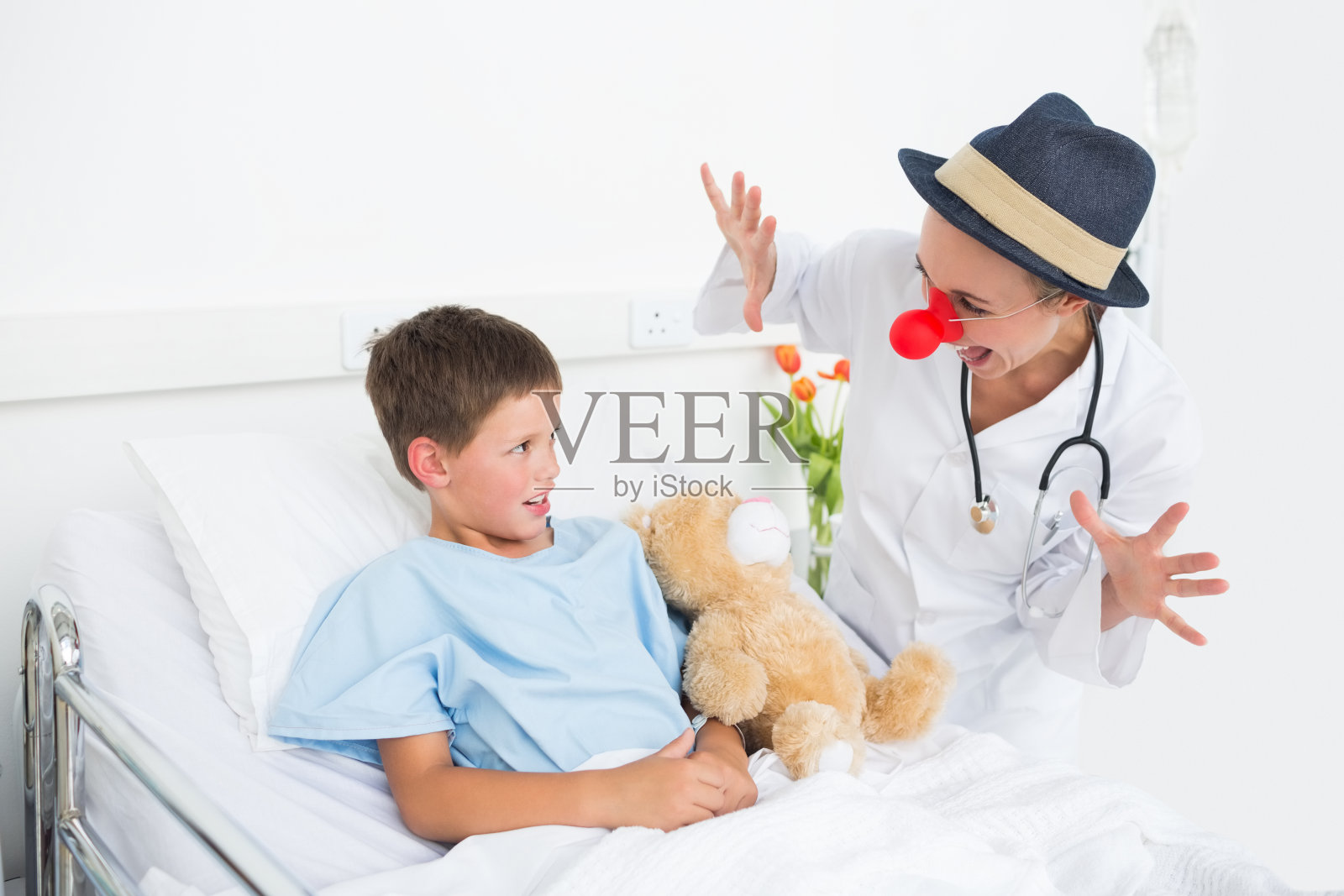 身穿小丑服的医生在医院里款待生病的男孩照片摄影图片