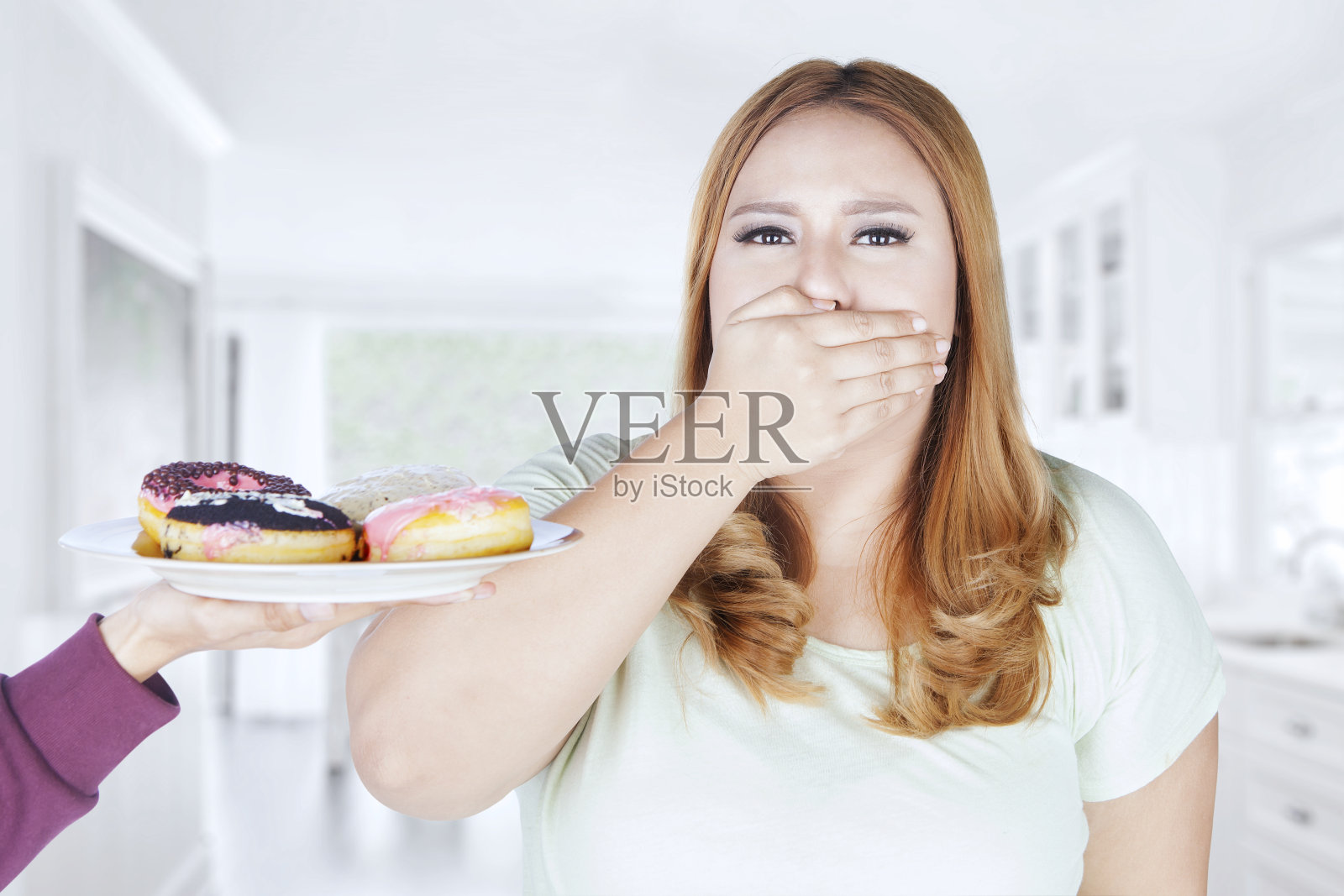 胖女人闭着嘴吃甜甜圈照片摄影图片