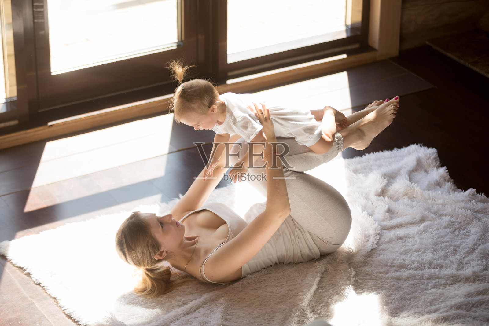 年轻的微笑瑜伽母亲和婴儿在家里锻炼照片摄影图片