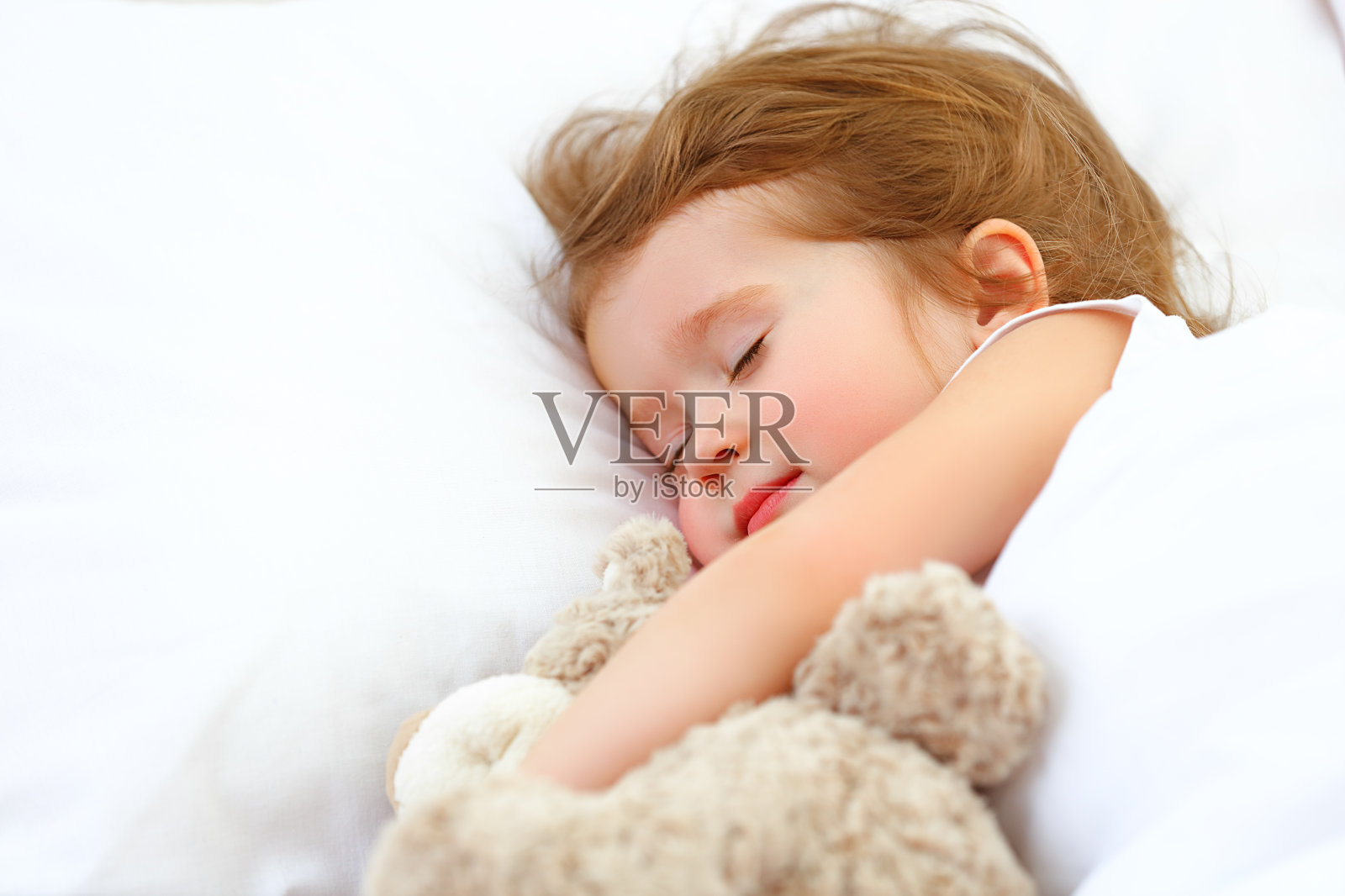 小女孩和泰迪熊睡在床上照片摄影图片