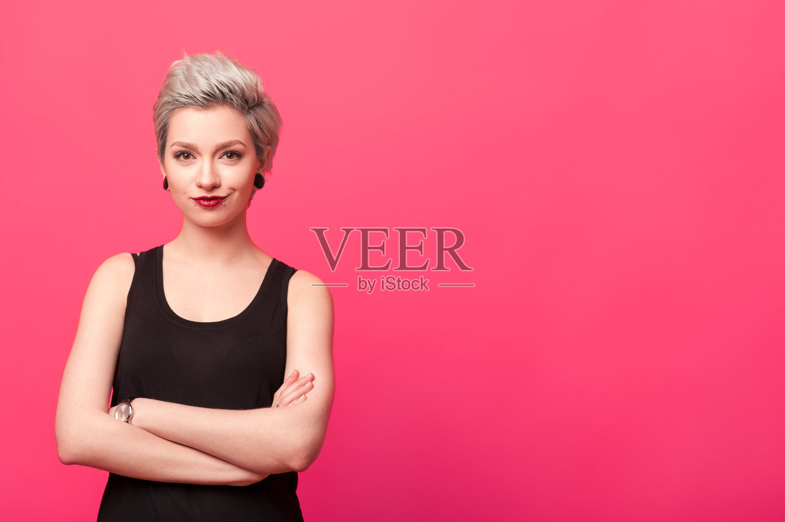 自信的女人双臂交叉，孤立地站在粉红色的背景上照片摄影图片