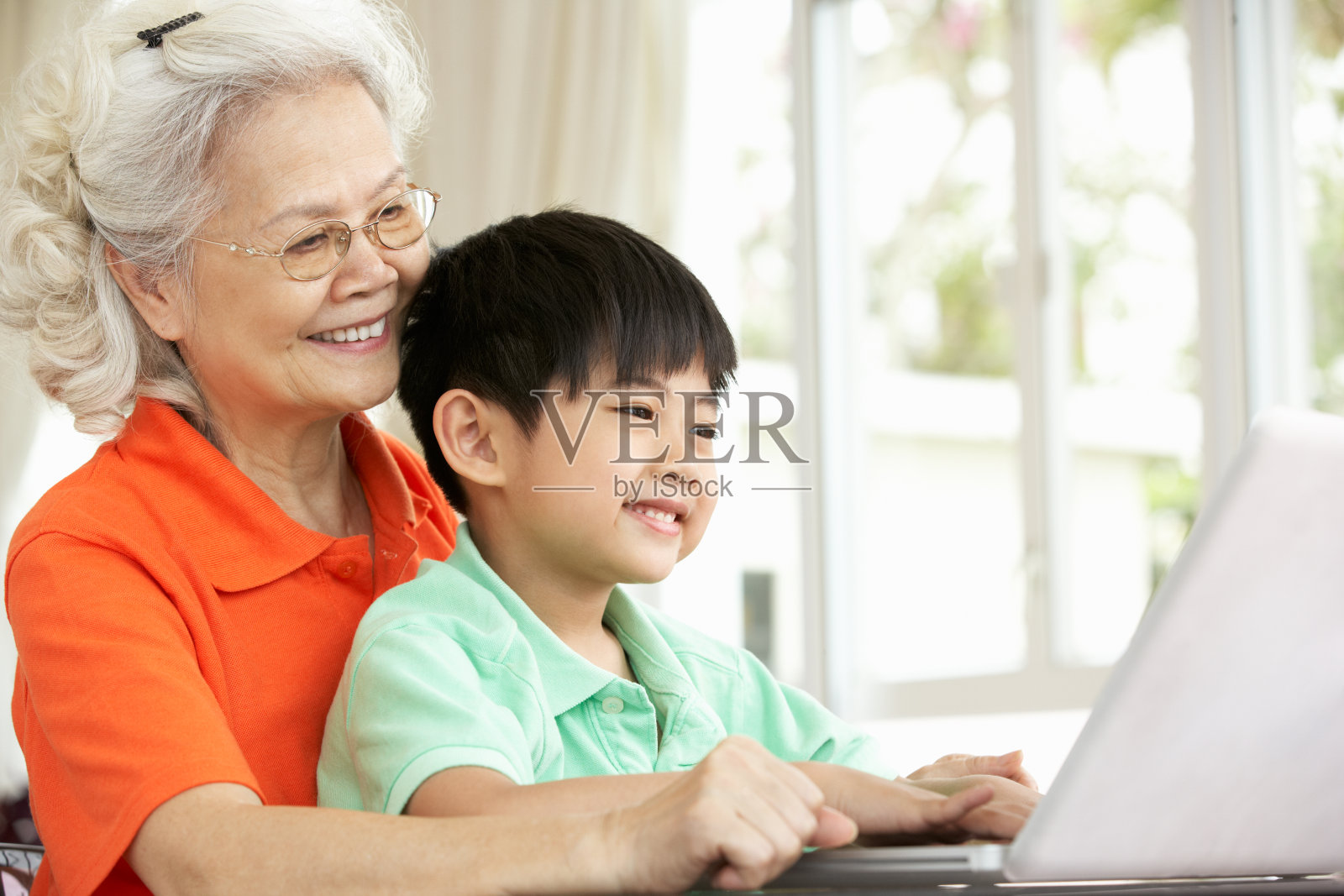 中国祖母和孙子坐在书桌前使用笔记本电脑照片摄影图片