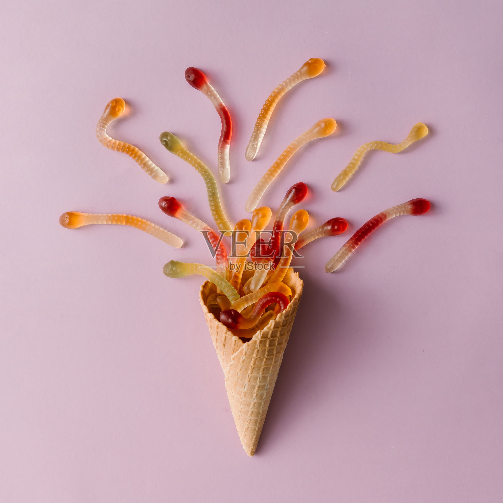 淡粉色背景上有软糖的冰淇淋蛋卷。最小的食品的概念。平的。照片摄影图片