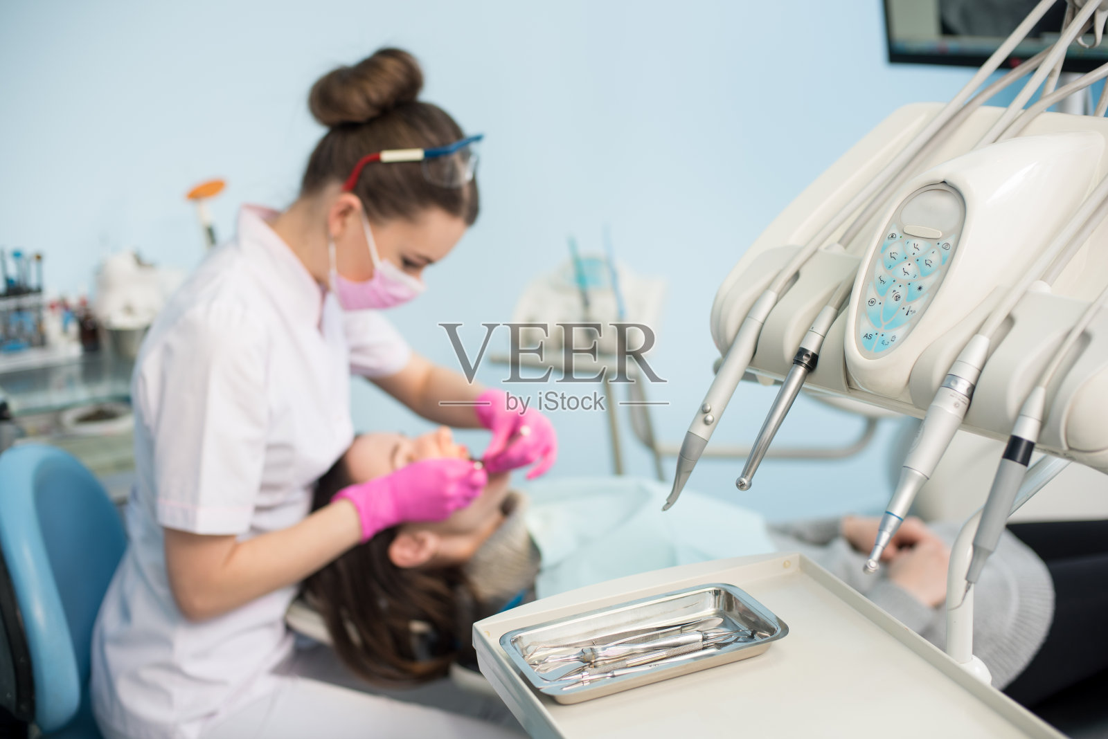 专业的牙科器械为首次检查，背景模糊的牙科医生正在牙科诊所治疗病人。有选择性的重点。口腔学照片摄影图片