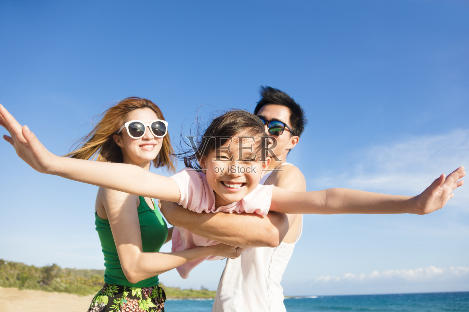 快乐的年轻家庭在海滩玩照片摄影图片