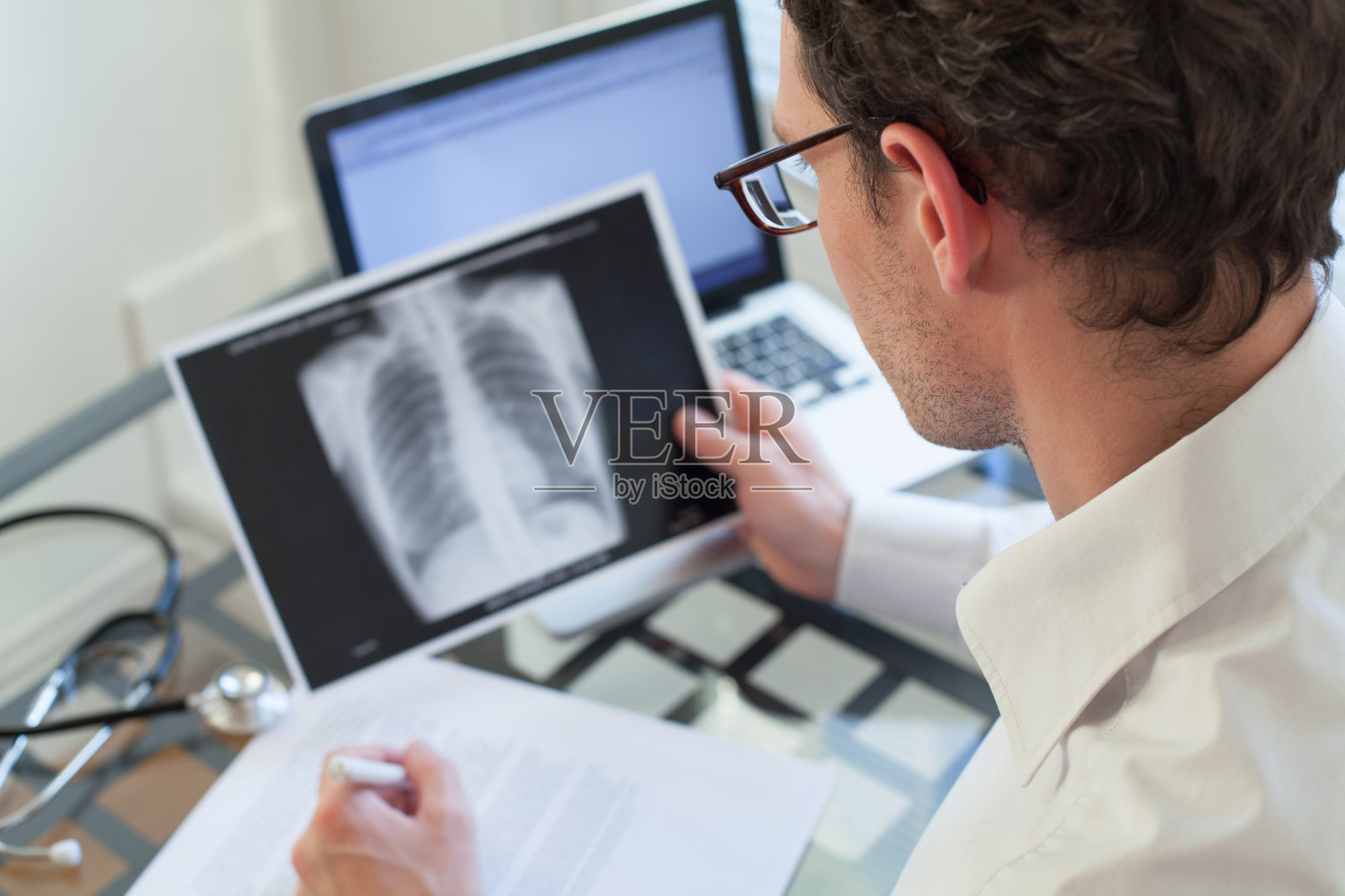 医生在看肺部x光片并写下诊断照片摄影图片
