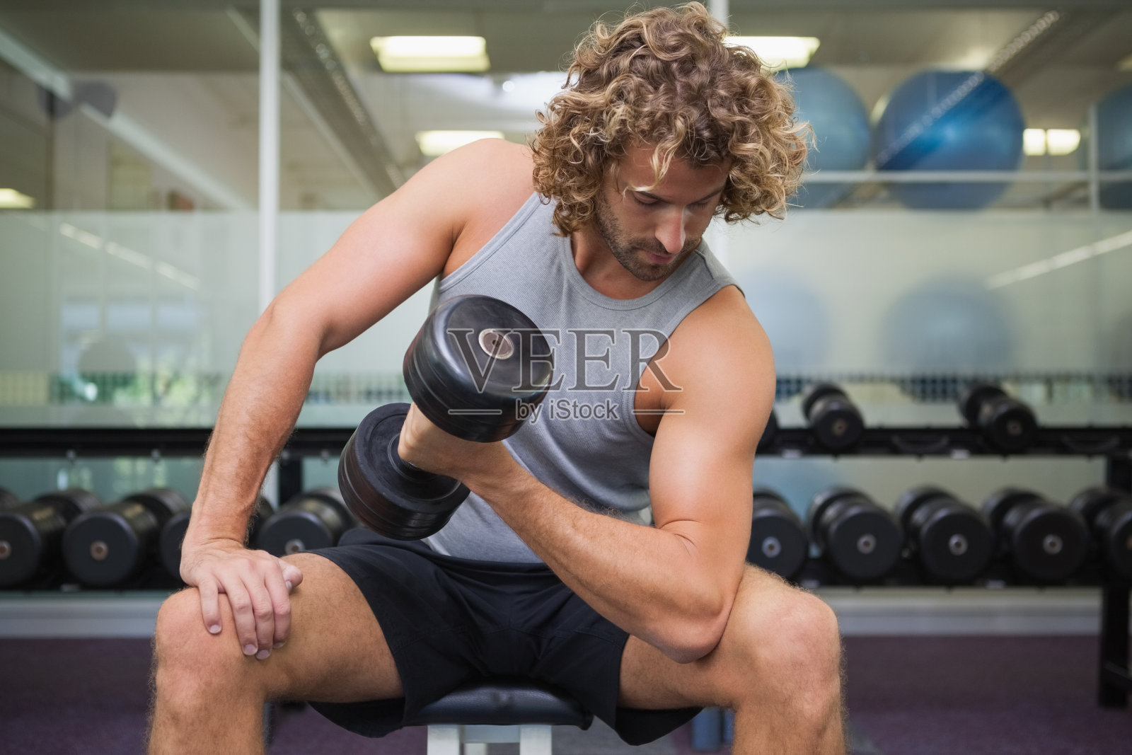 一个年轻人在健身房用哑铃锻炼照片摄影图片