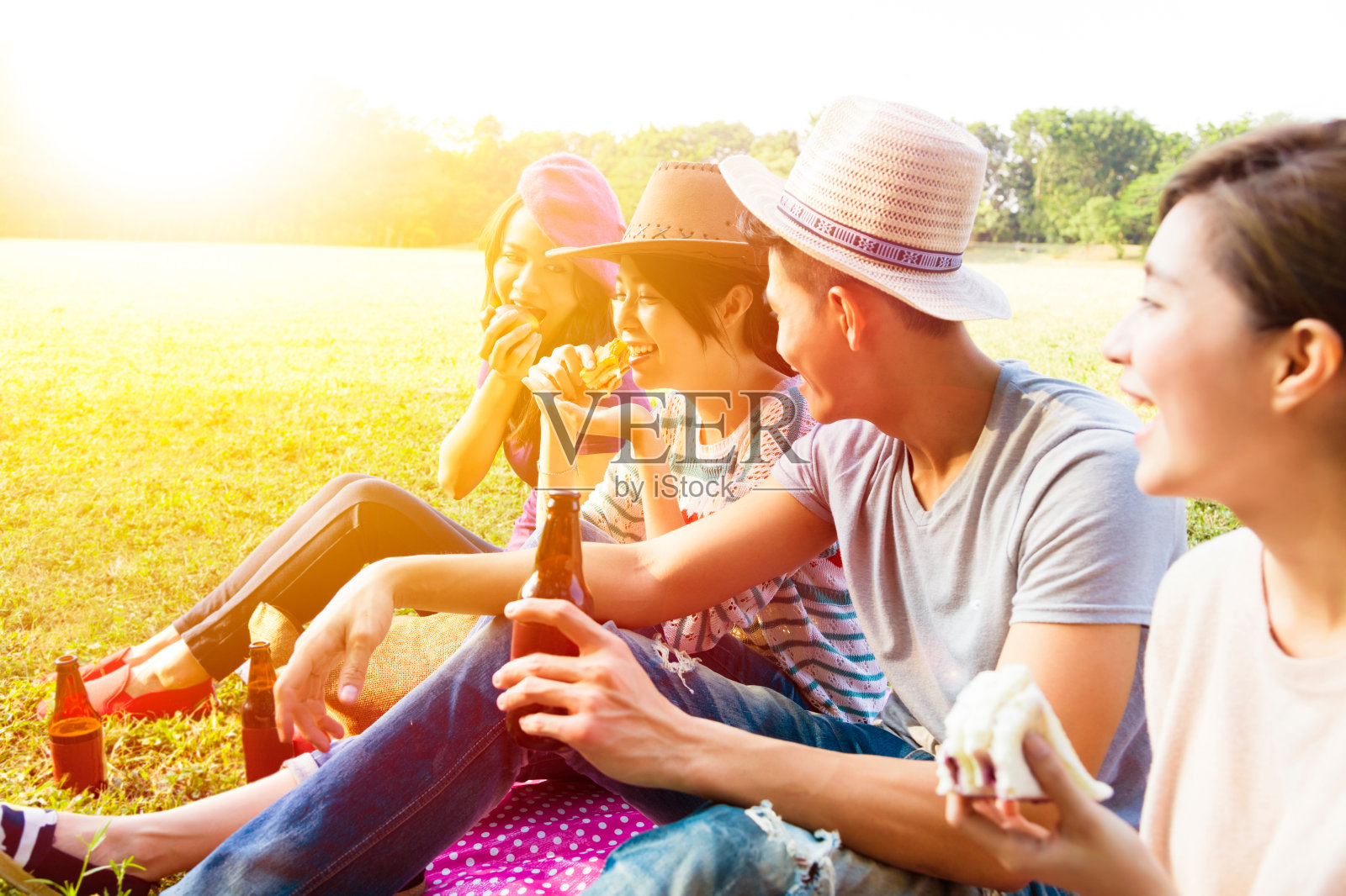 快乐的年轻朋友享受野餐和吃照片摄影图片