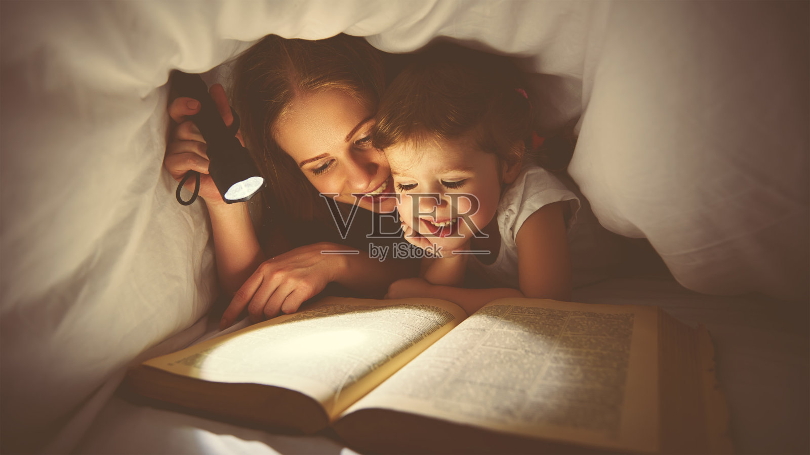 家庭阅读睡觉。妈妈和孩子在看书照片摄影图片