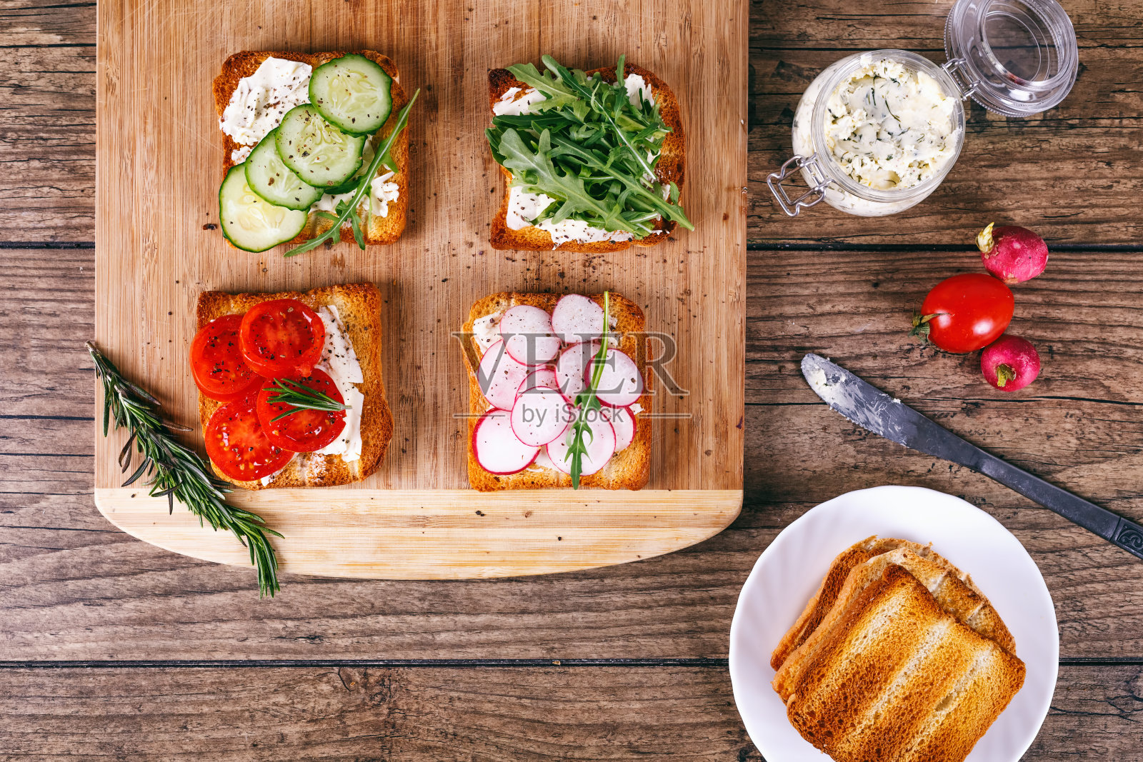 四个三明治与新鲜蔬菜，西红柿，黄瓜，萝卜和芝麻菜在木背景。自制黄油和吐司。俯视图照片摄影图片