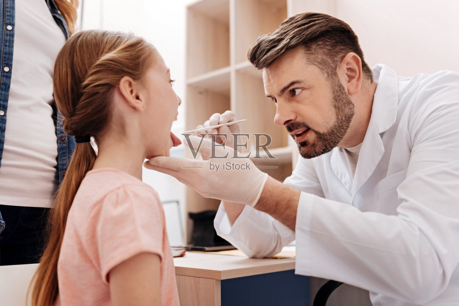 细心的儿科医生正在检查小女孩的喉咙照片摄影图片
