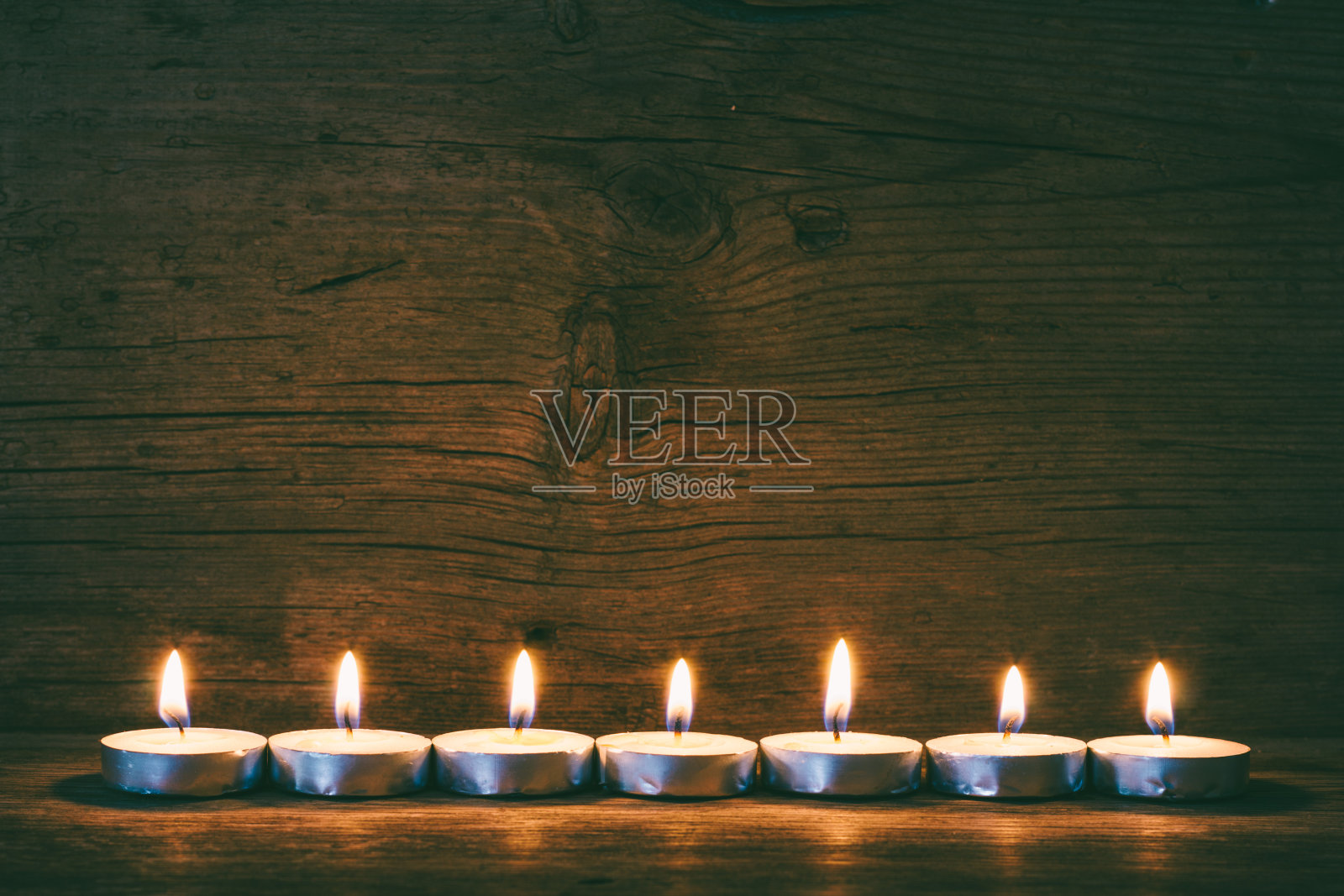 燃着的蜡烛在旧谷仓板的背景上，着色的照片照片摄影图片