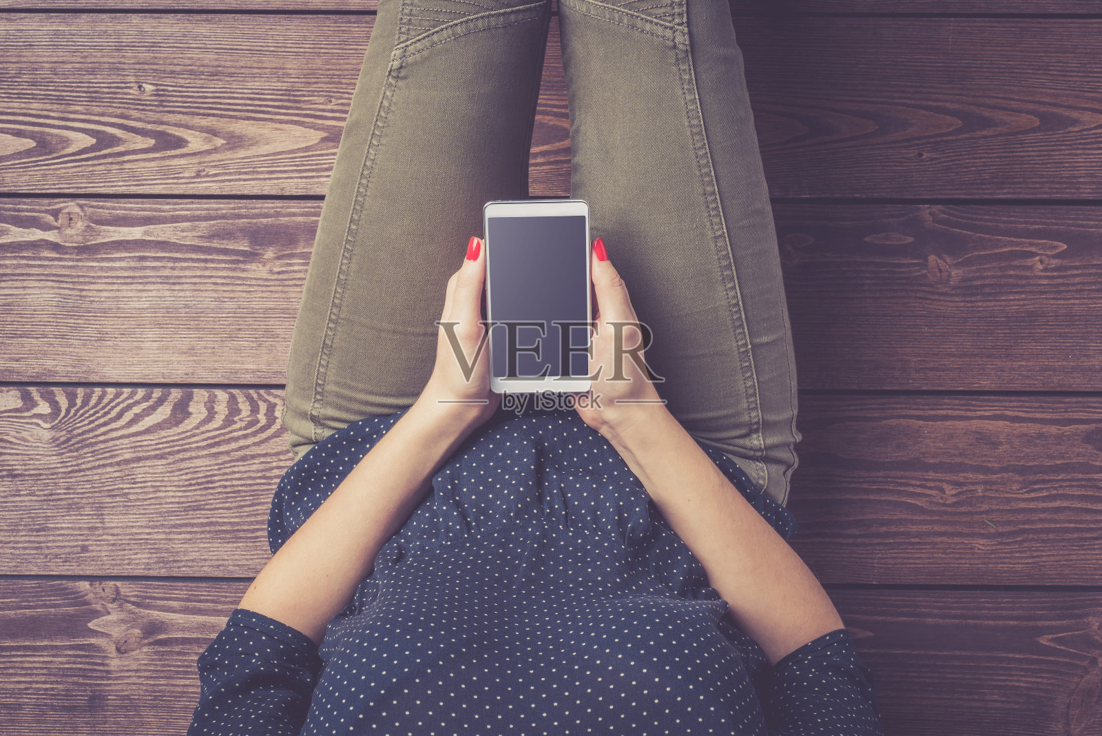 一名年轻女子坐在地板上使用智能手机的照片照片摄影图片