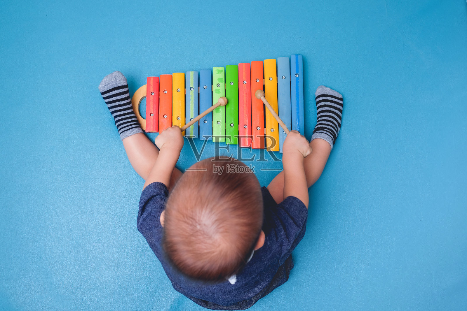 鸟瞰图可爱的小亚洲18个月/ 1岁的婴儿男孩孩子拿木棍和弹奏乐器彩色木制玩具木琴照片摄影图片