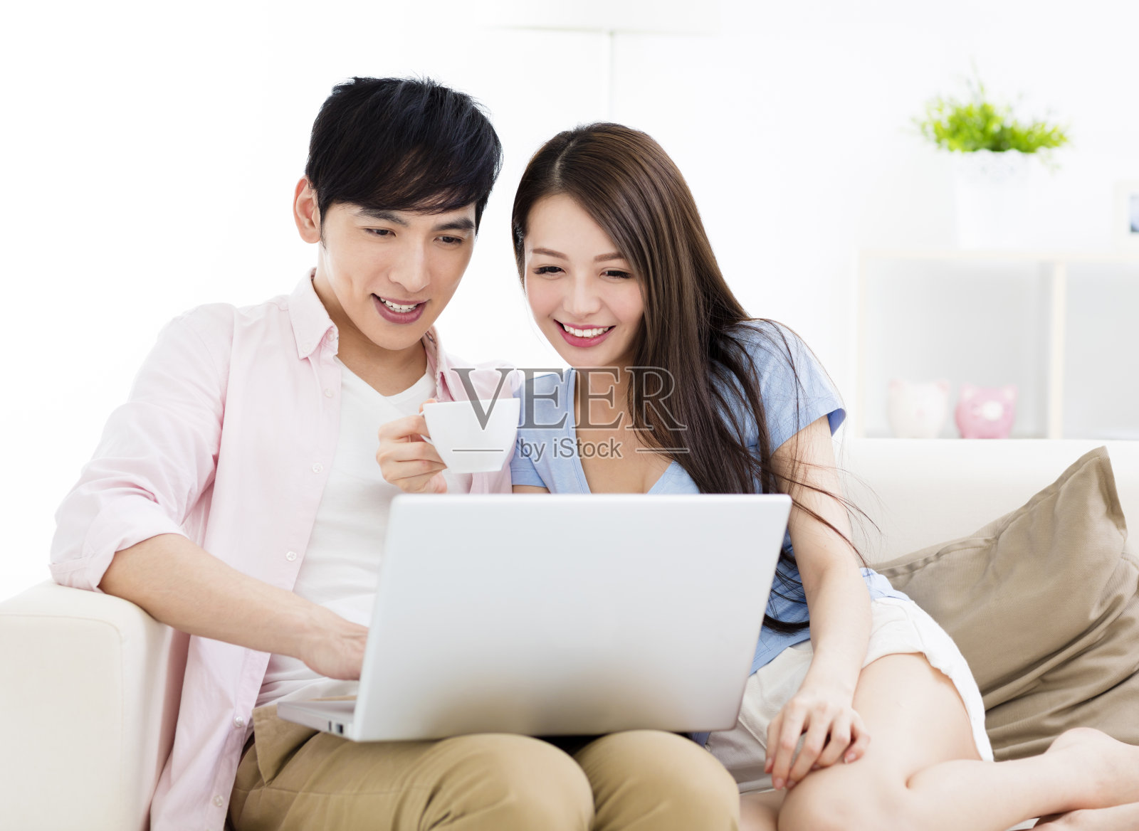 一对幸福的年轻夫妇坐在沙发上用笔记本电脑照片摄影图片