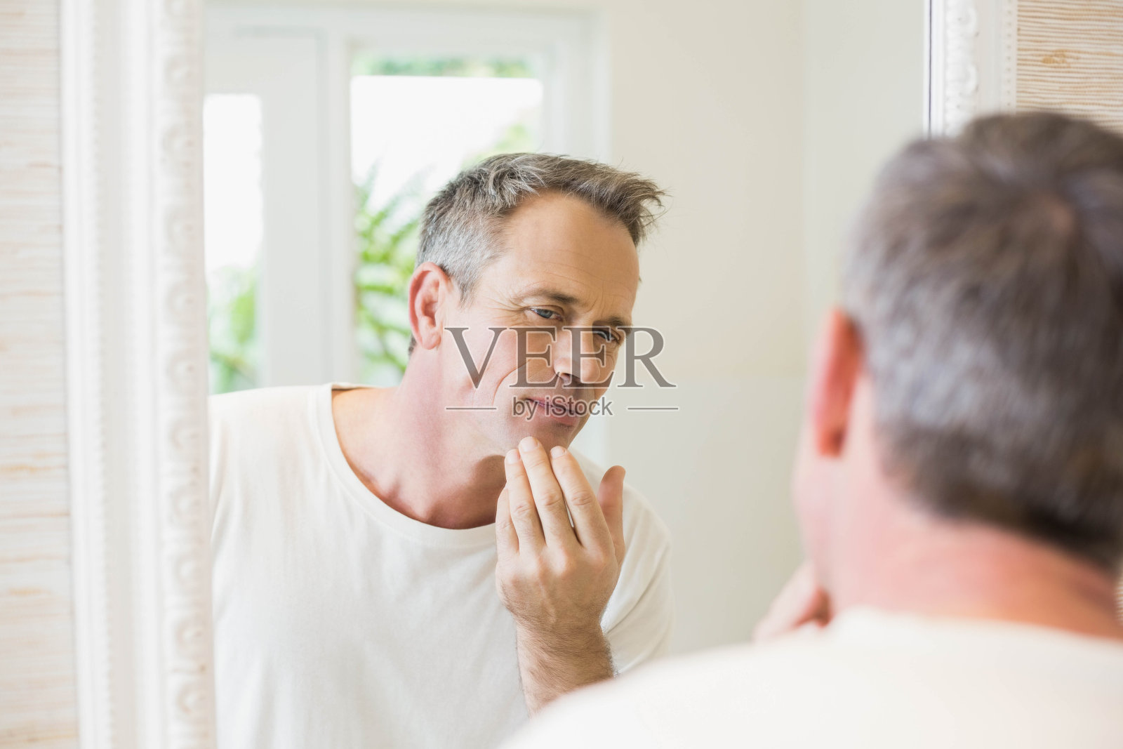 英俊的男人看着镜子里的自己照片摄影图片