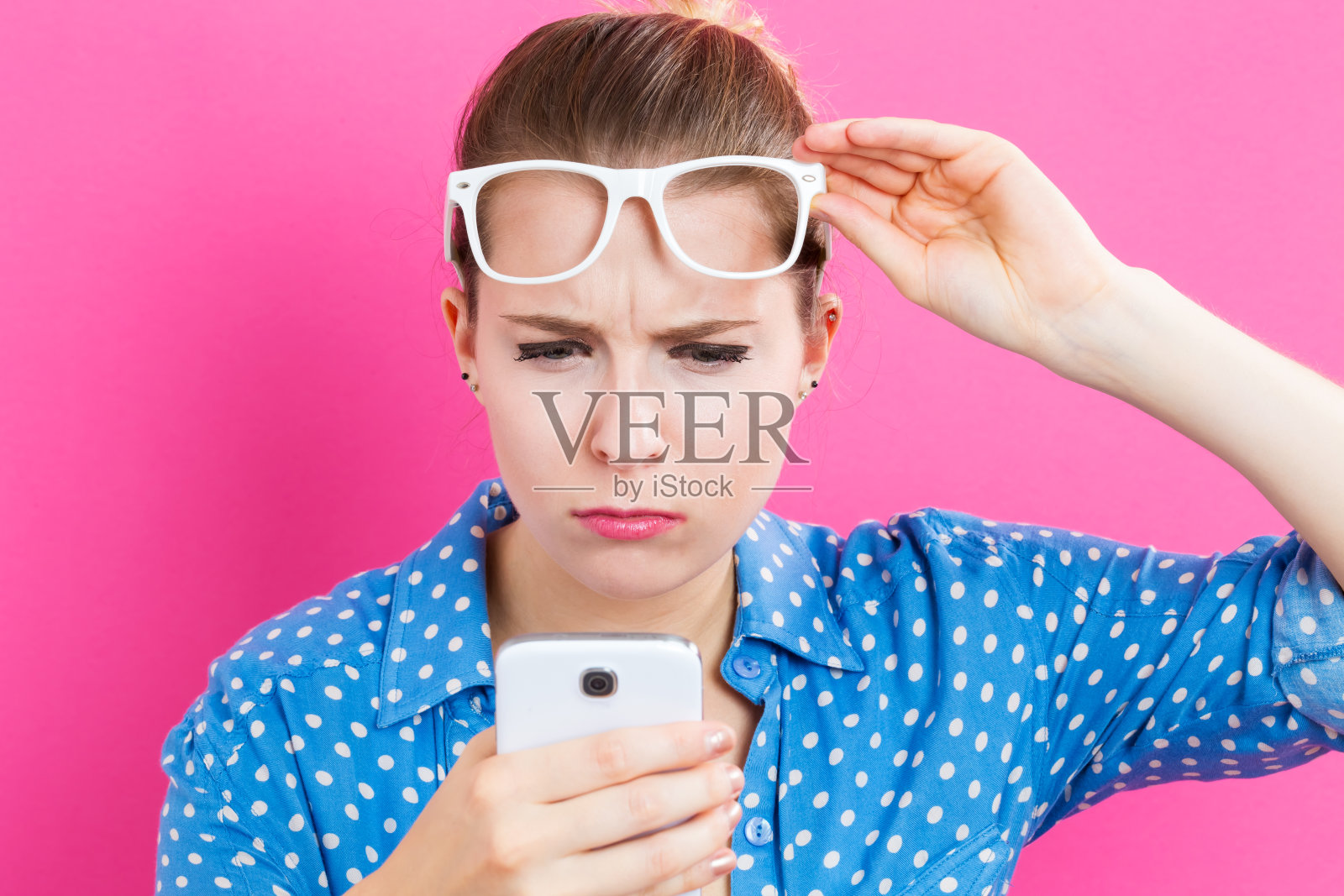 年轻女子盯着手机看照片摄影图片