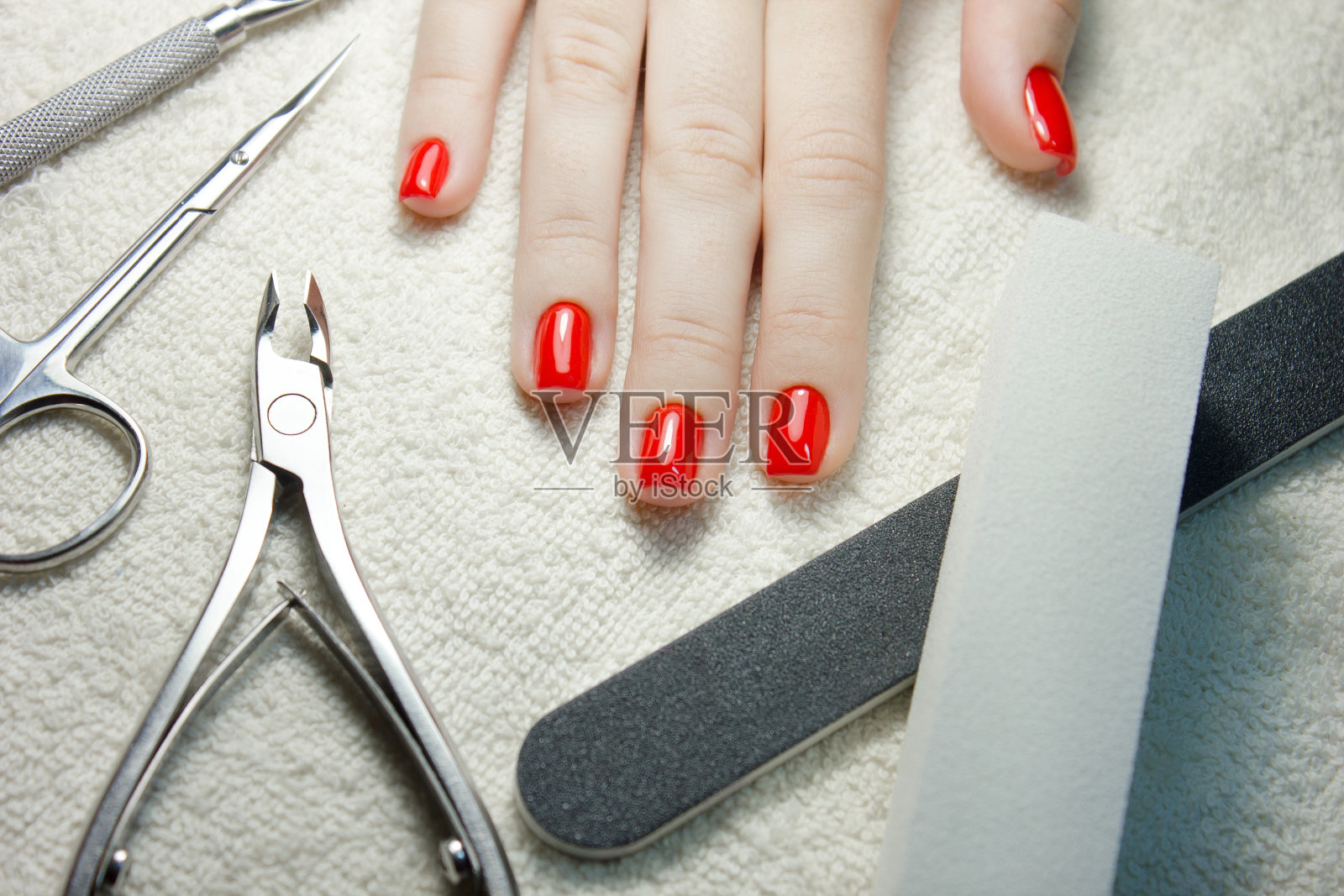 修剪过的红色指甲与指甲工具在白色毛巾照片摄影图片