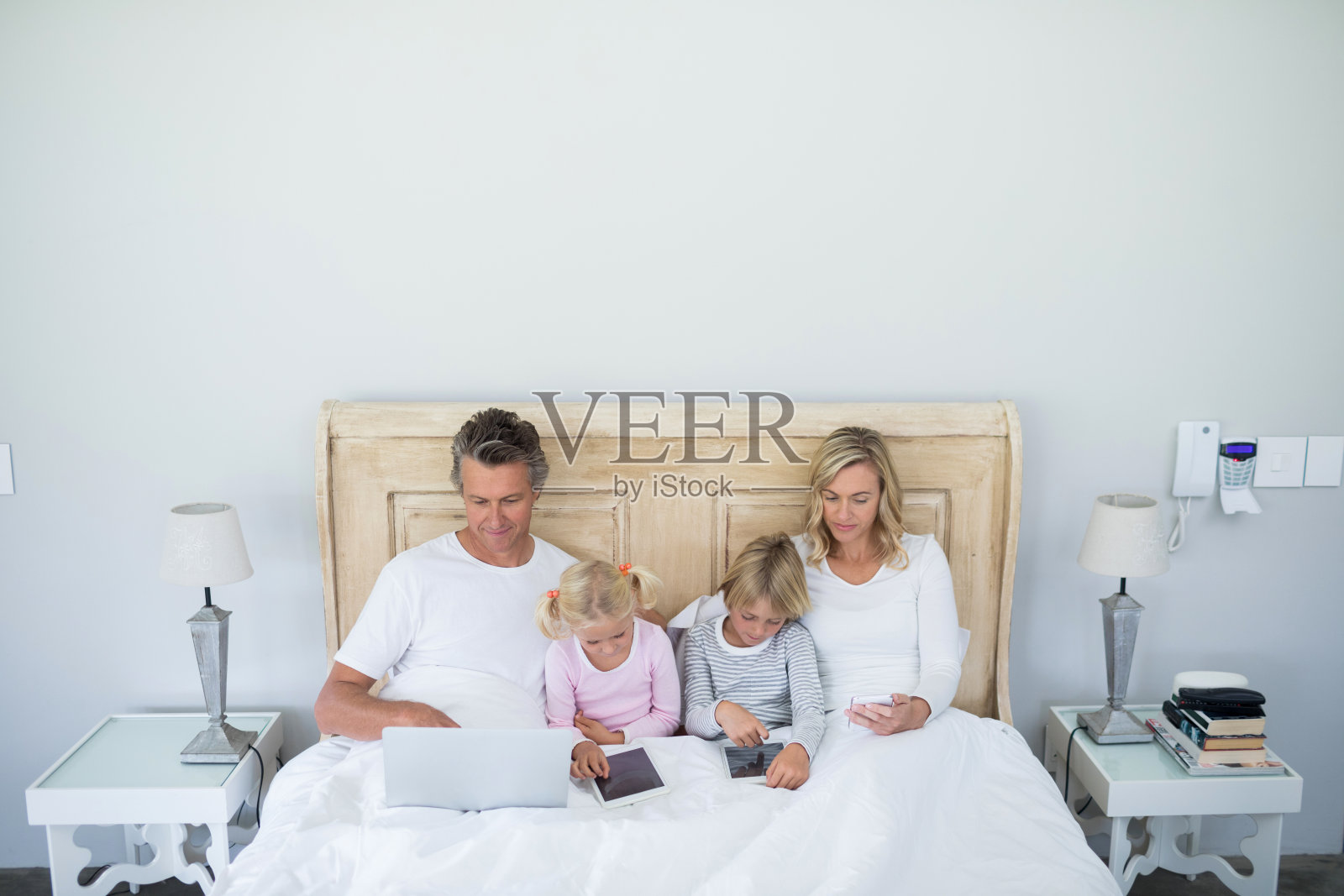 家庭使用数字平板电脑，手机和笔记本电脑在床上的卧室照片摄影图片