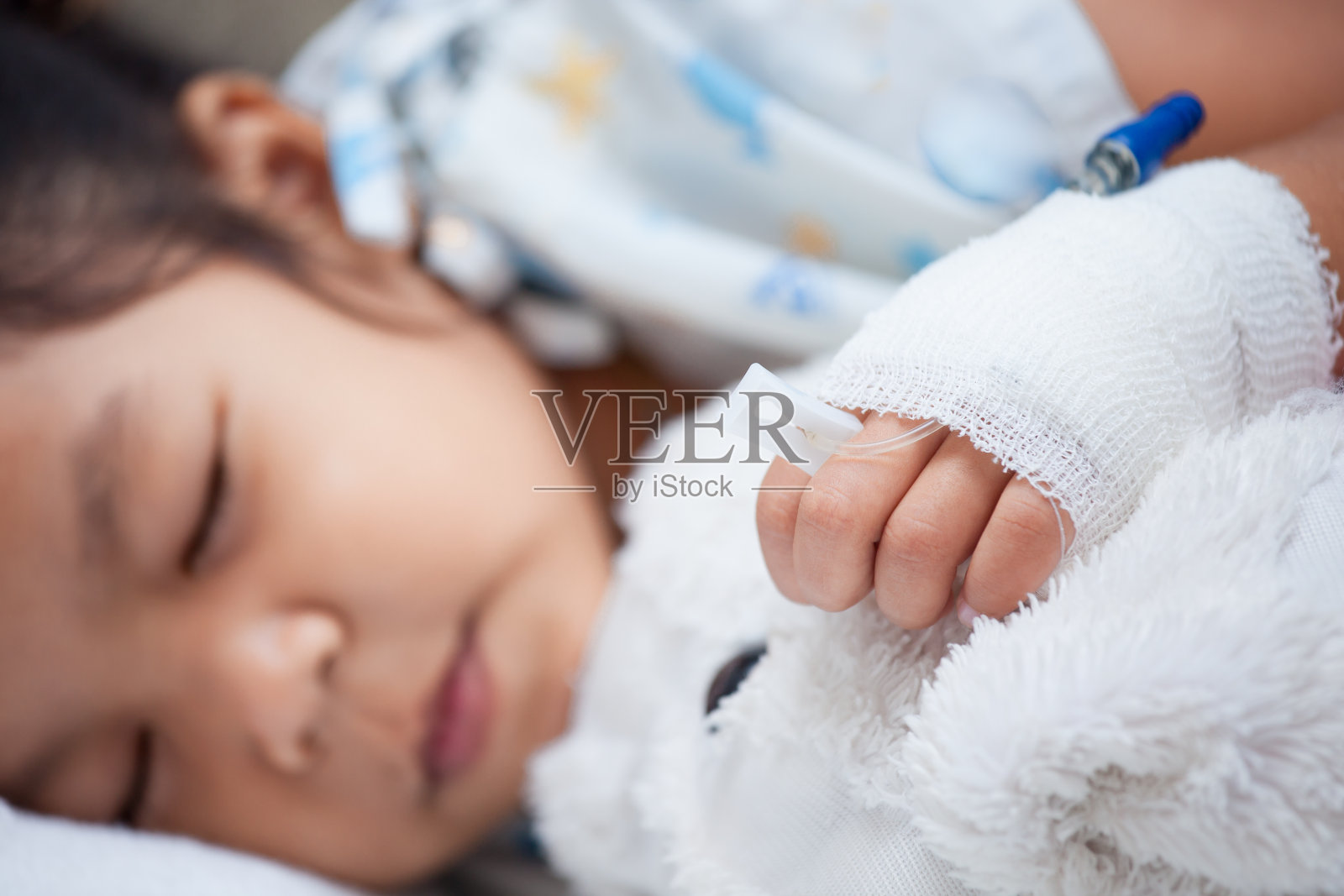 生病的小女孩用生理盐水的手在睡觉的时候抱着她的洋娃娃照片摄影图片