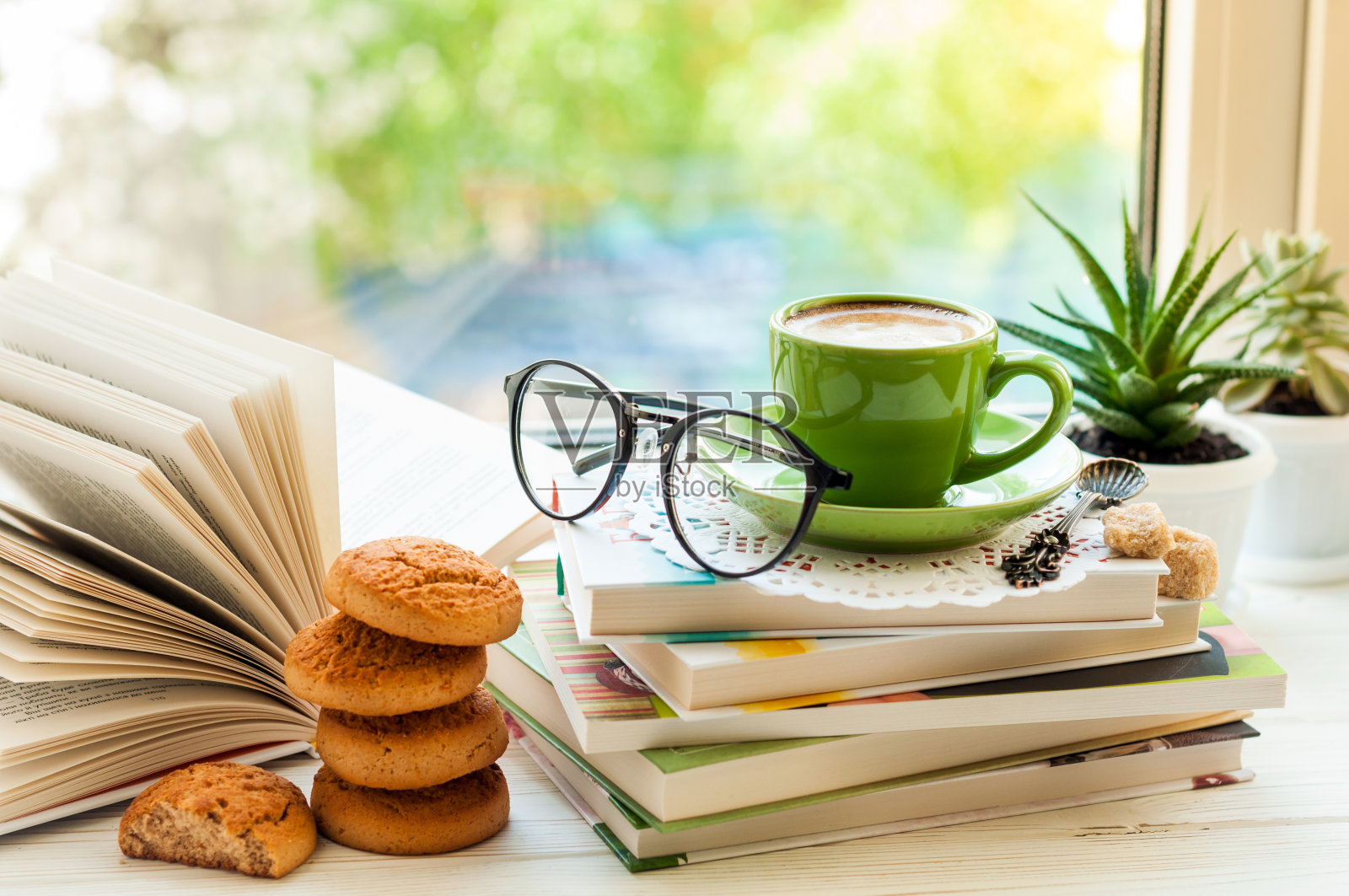 咖啡杯，打开的书，眼镜，饼干和花的窗户与散。阅读和早餐。温馨舒适的室内概念照片摄影图片