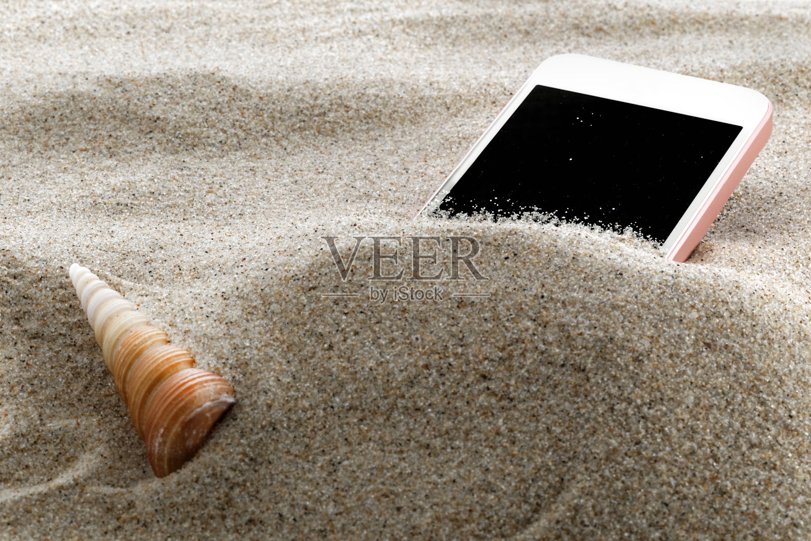 把手机放在沙滩上的沙子里照片摄影图片