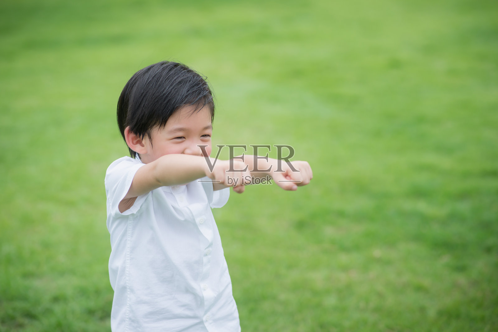 穿着白色衣服的亚洲小孩在绿色的草地上玩耍照片摄影图片